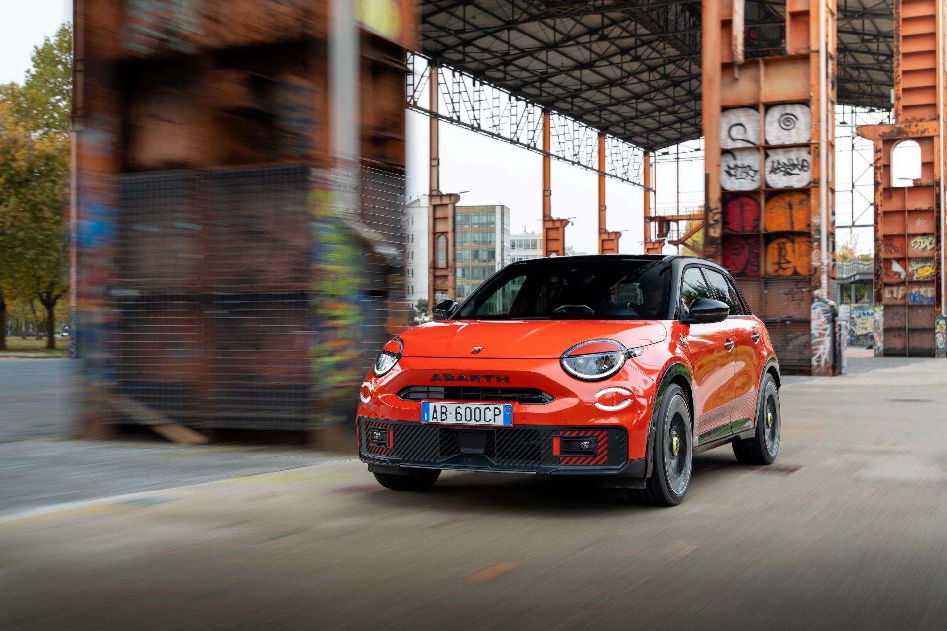 2025 abarth 600e driving front three quarter urban orange