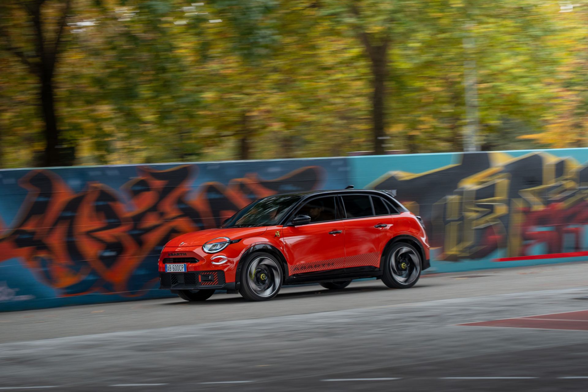 2025 abarth 600e driving side profile graffiti wall orange