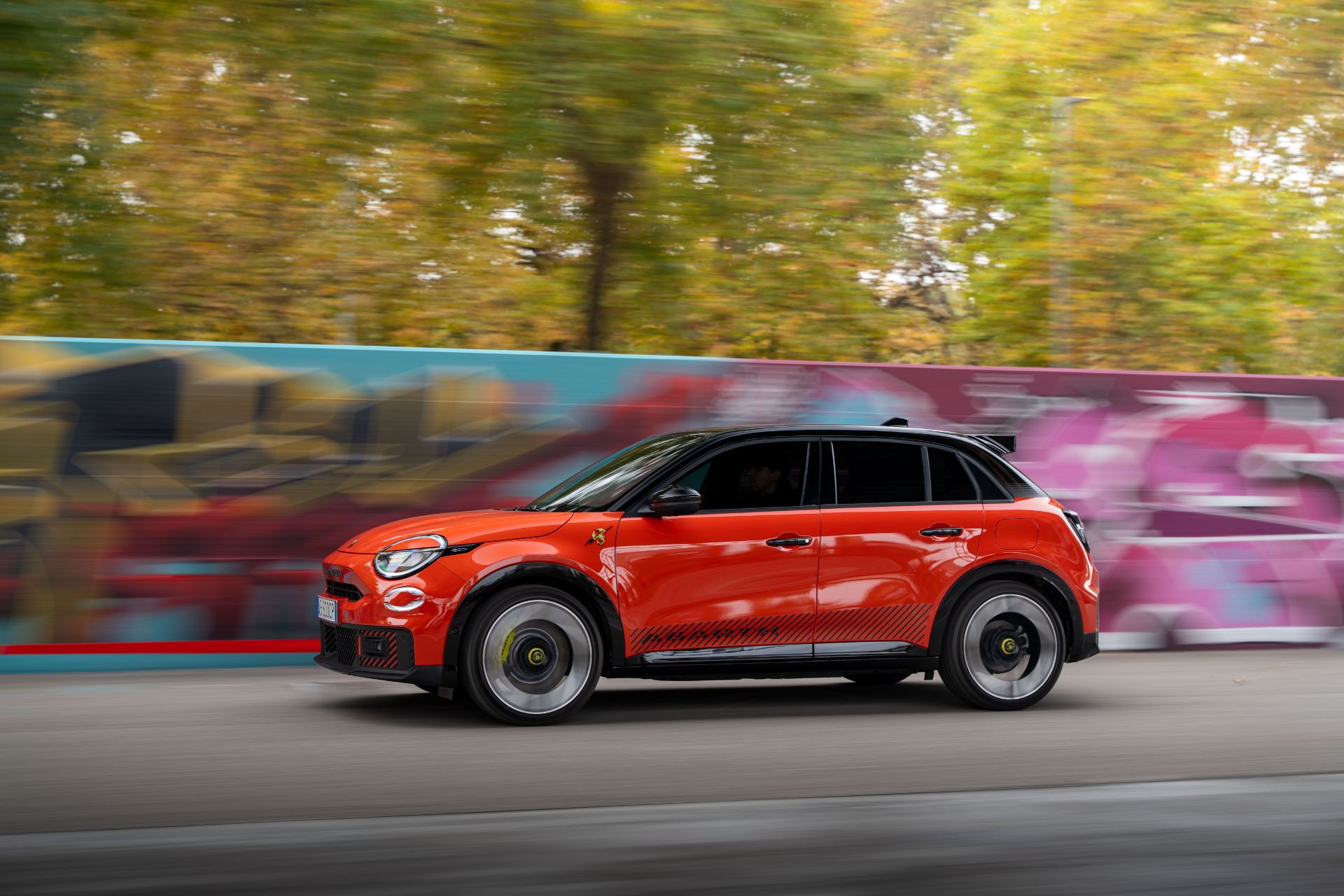 2025 abarth 600e driving side profile street art orange