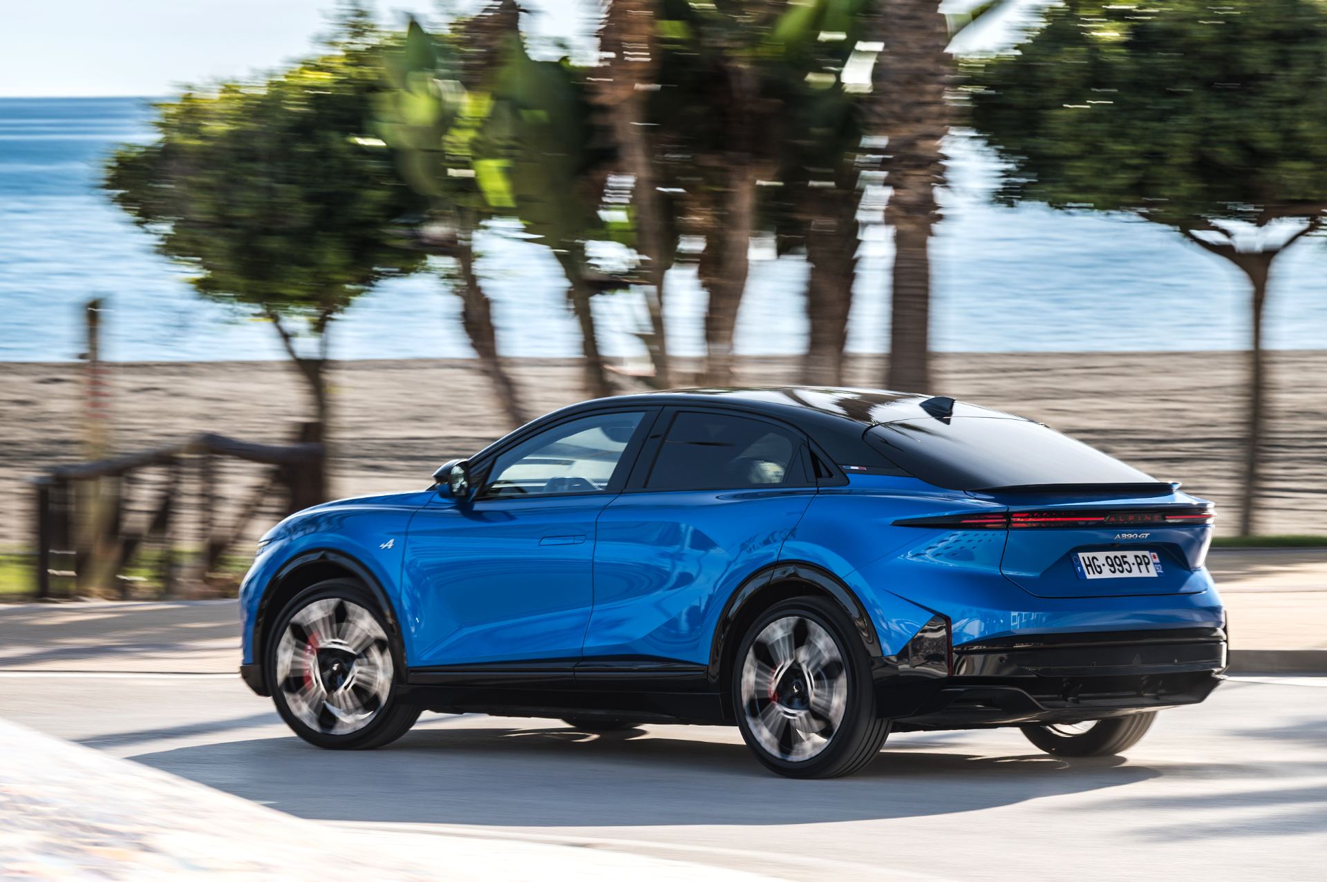2026 alpine a390 gt driving rear three quarter seafront alpine vision blue