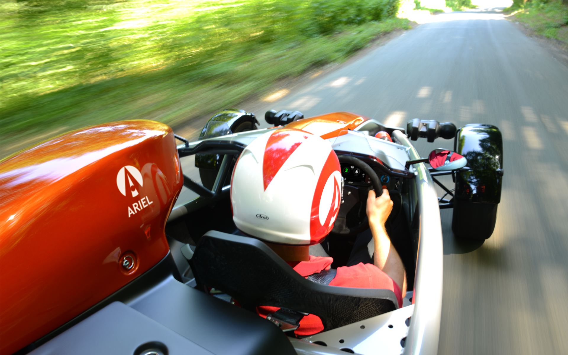 2026 ariel atom 4 driving over shoulder view orange