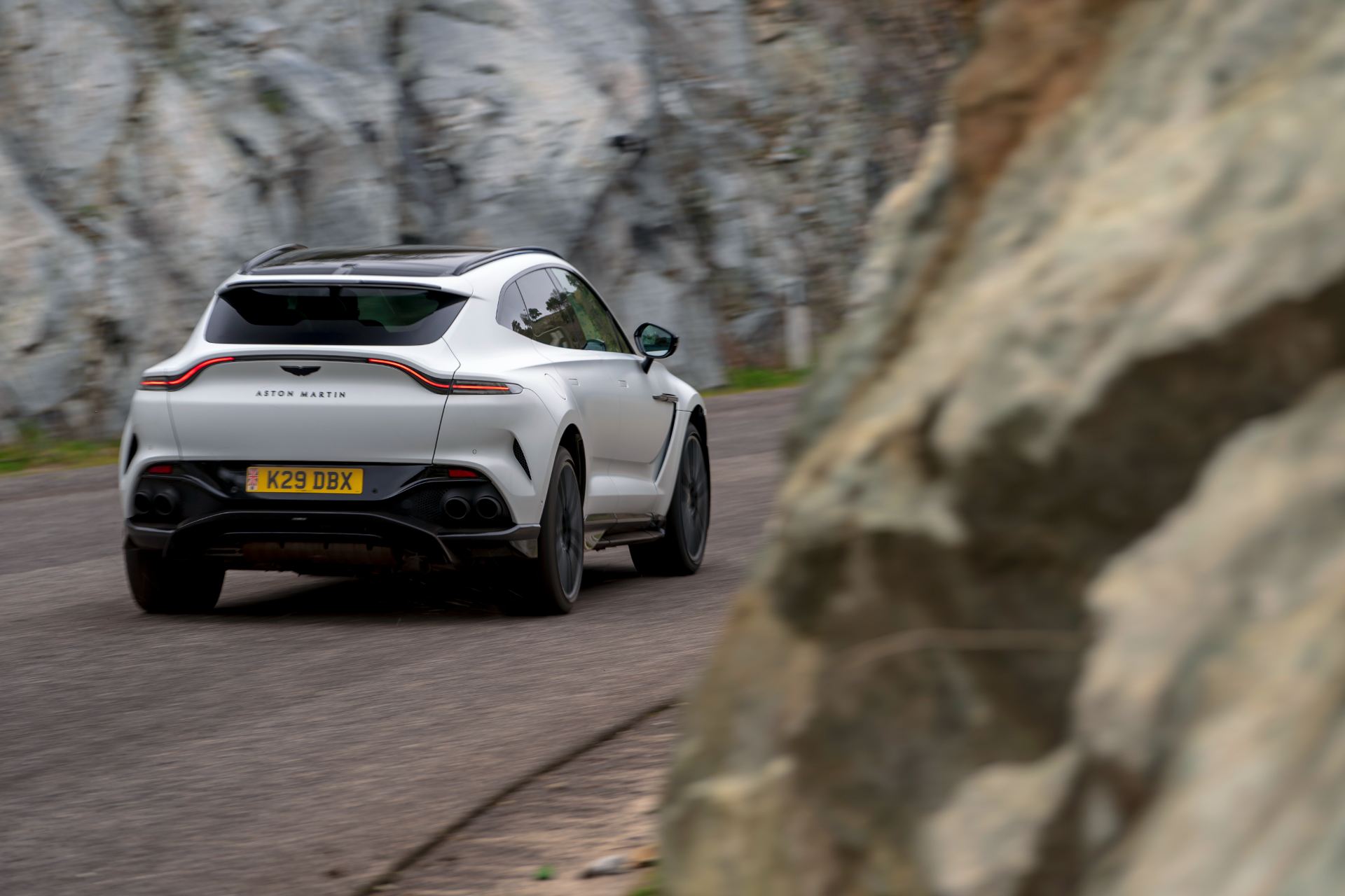 2026 aston martin dbx707 driving rear rock wall white