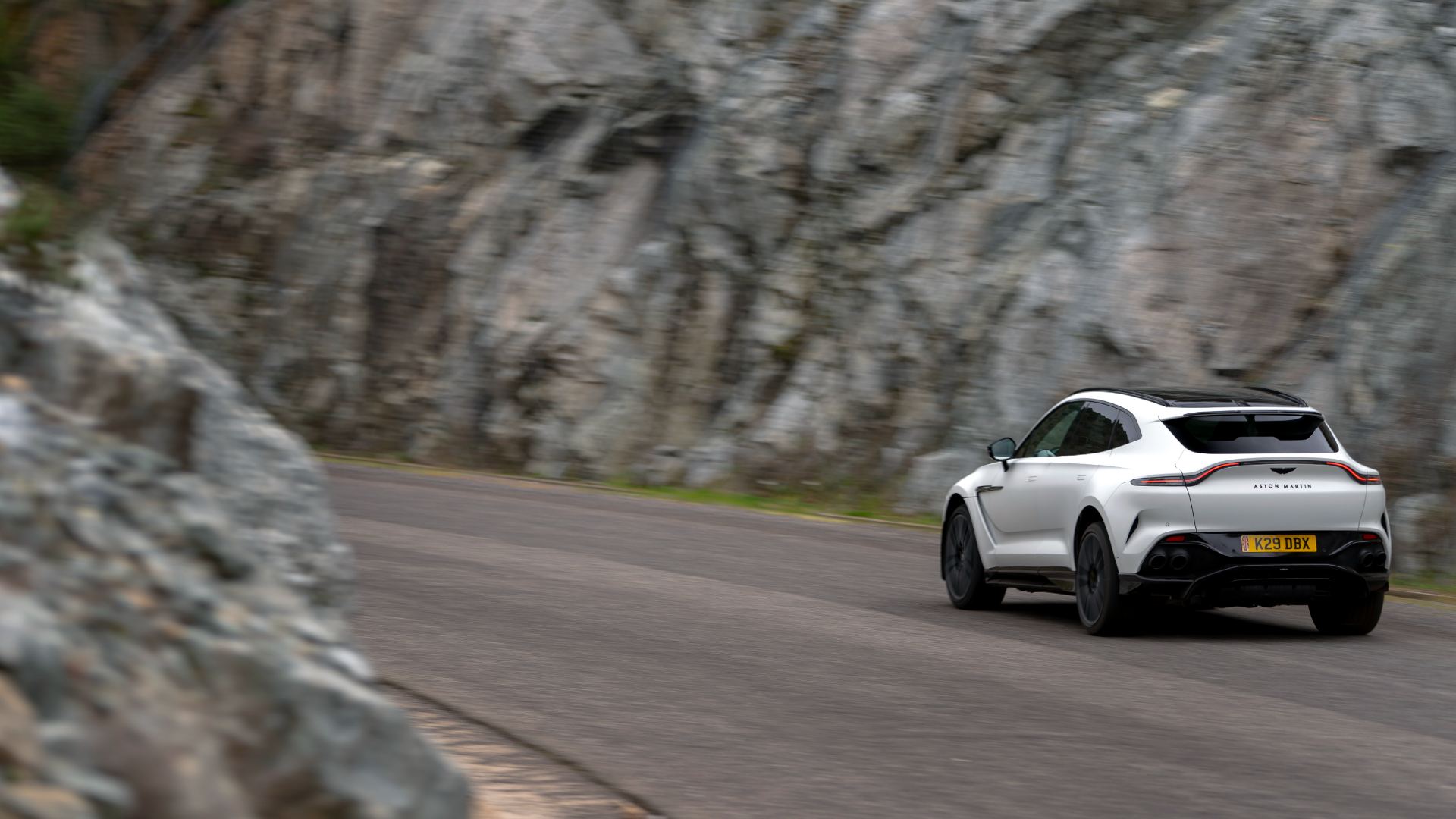2026 aston martin dbx707 driving rear three quarter canyon road white