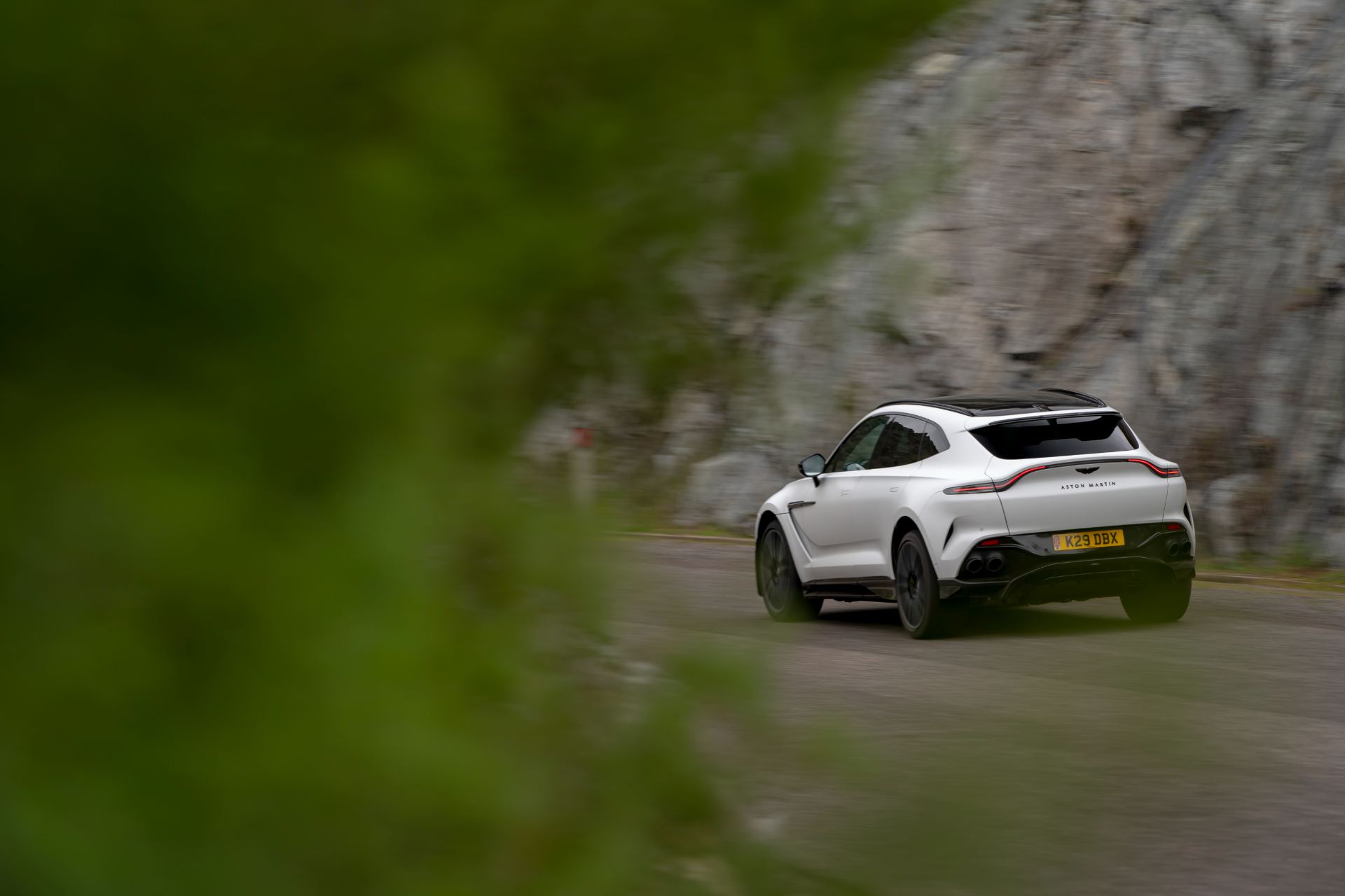 2026 aston martin dbx707 driving rear through foliage white