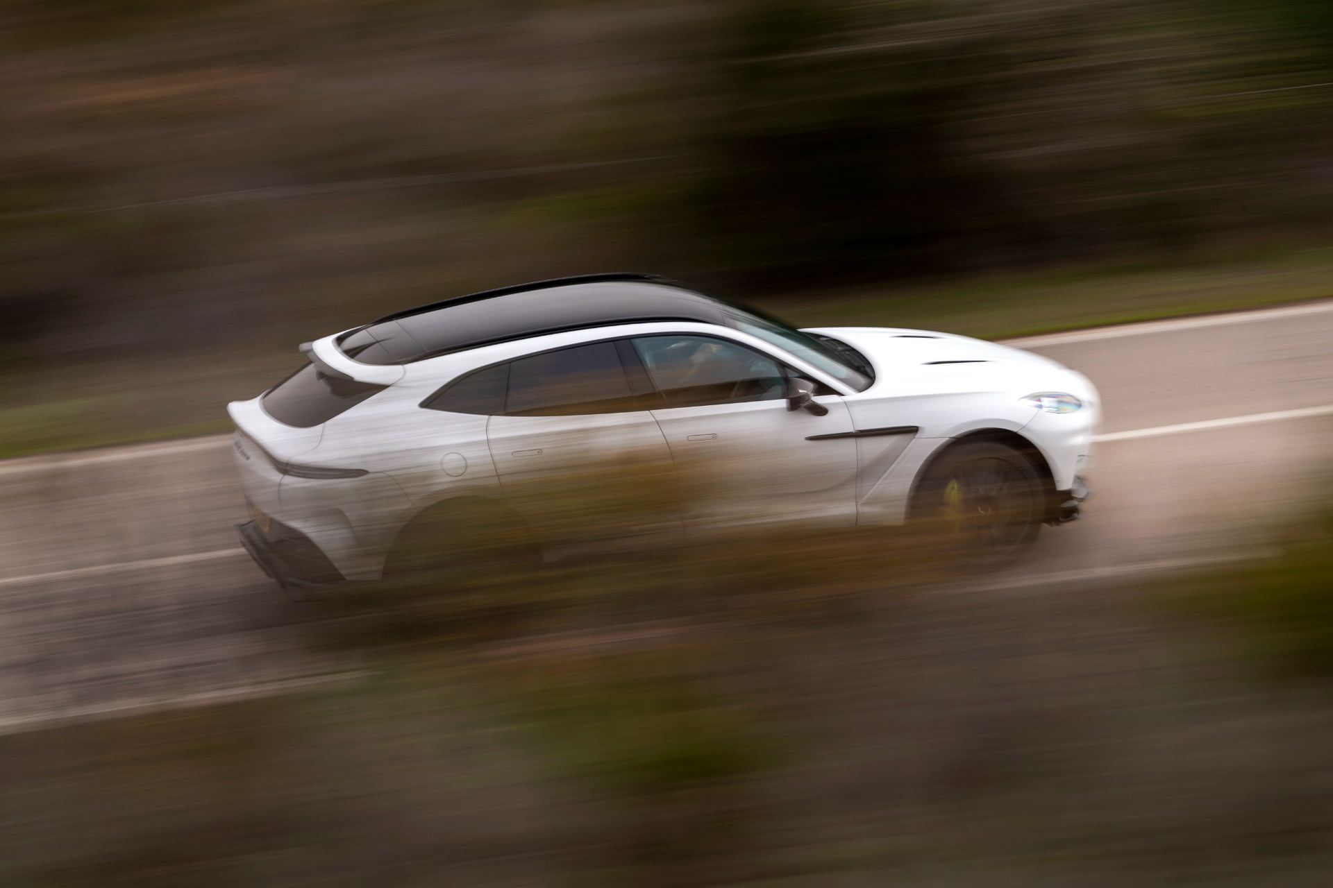 2026 aston martin dbx707 driving rear three quarter panning white