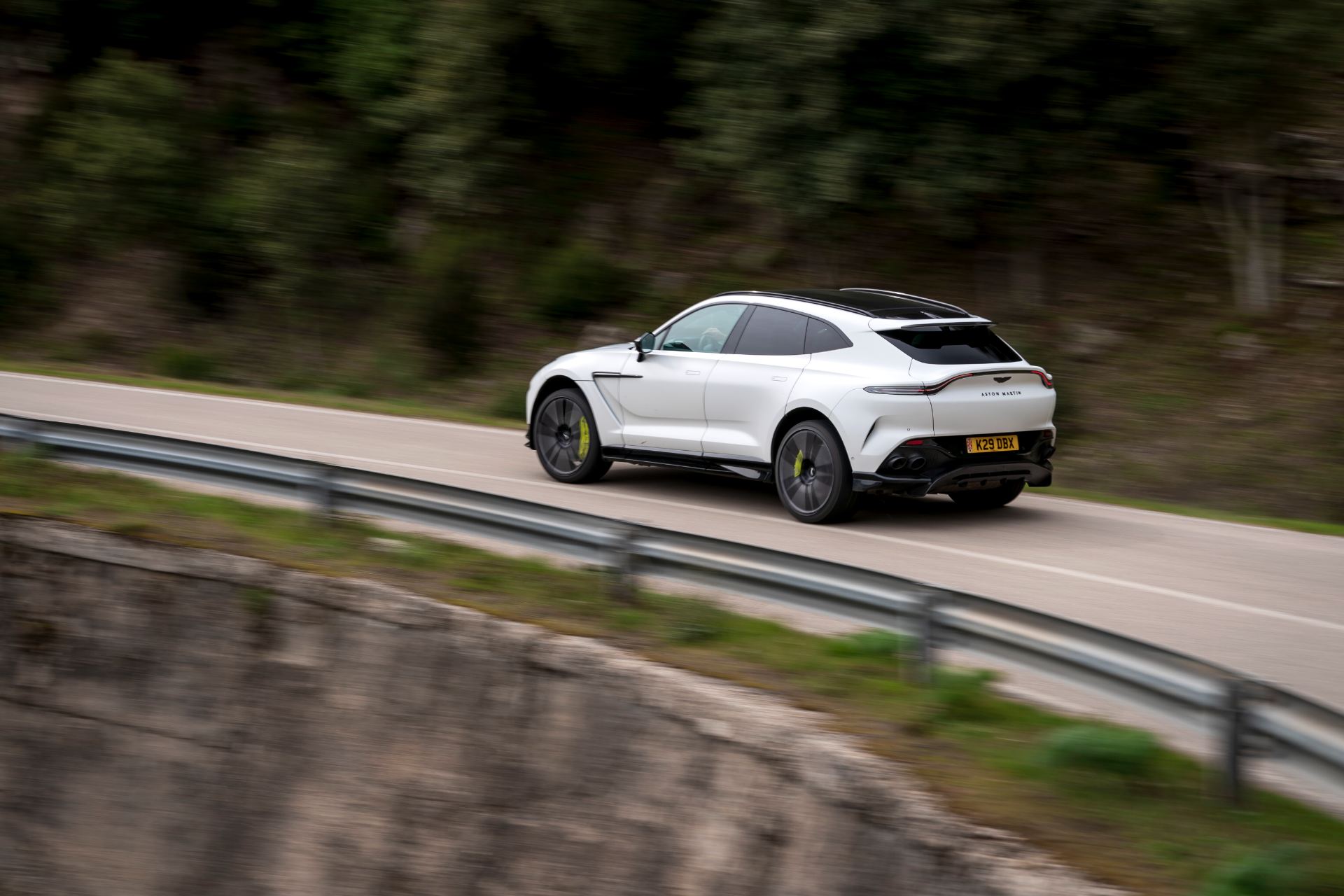 2026 aston martin dbx707 driving rear three quarter coastal road white