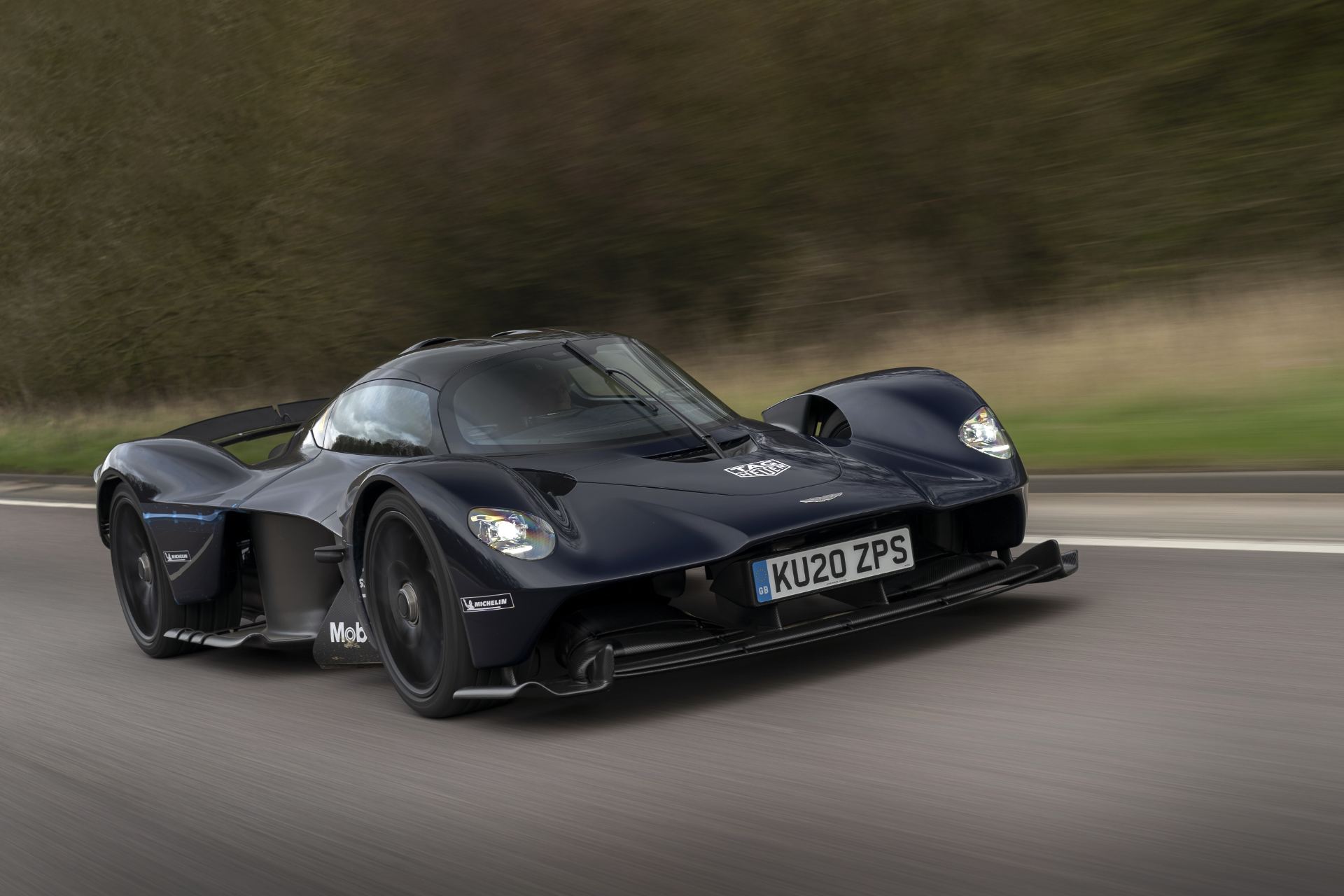 2026 aston martin valkyrie driving front three quarter panning dark blue
