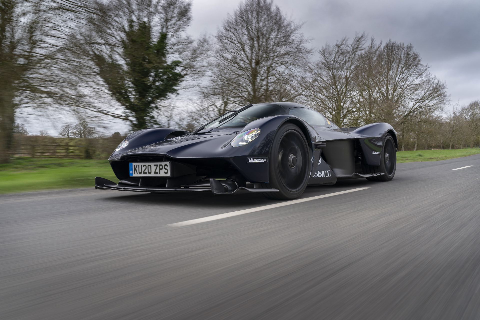 2026 aston martin valkyrie driving front three quarter trees dark blue