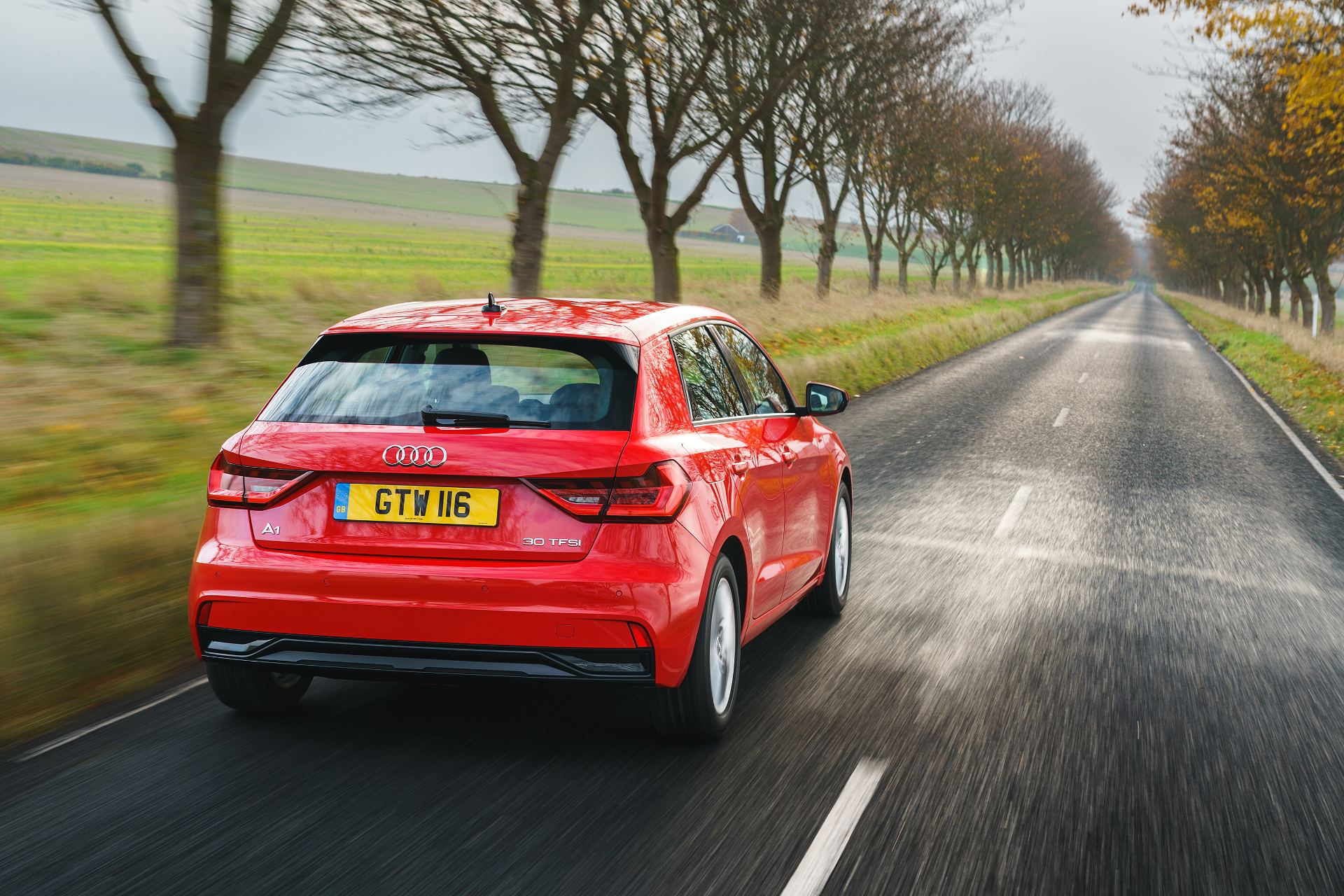 2026 audi a1 sportback sport driving rear tree lined road red
