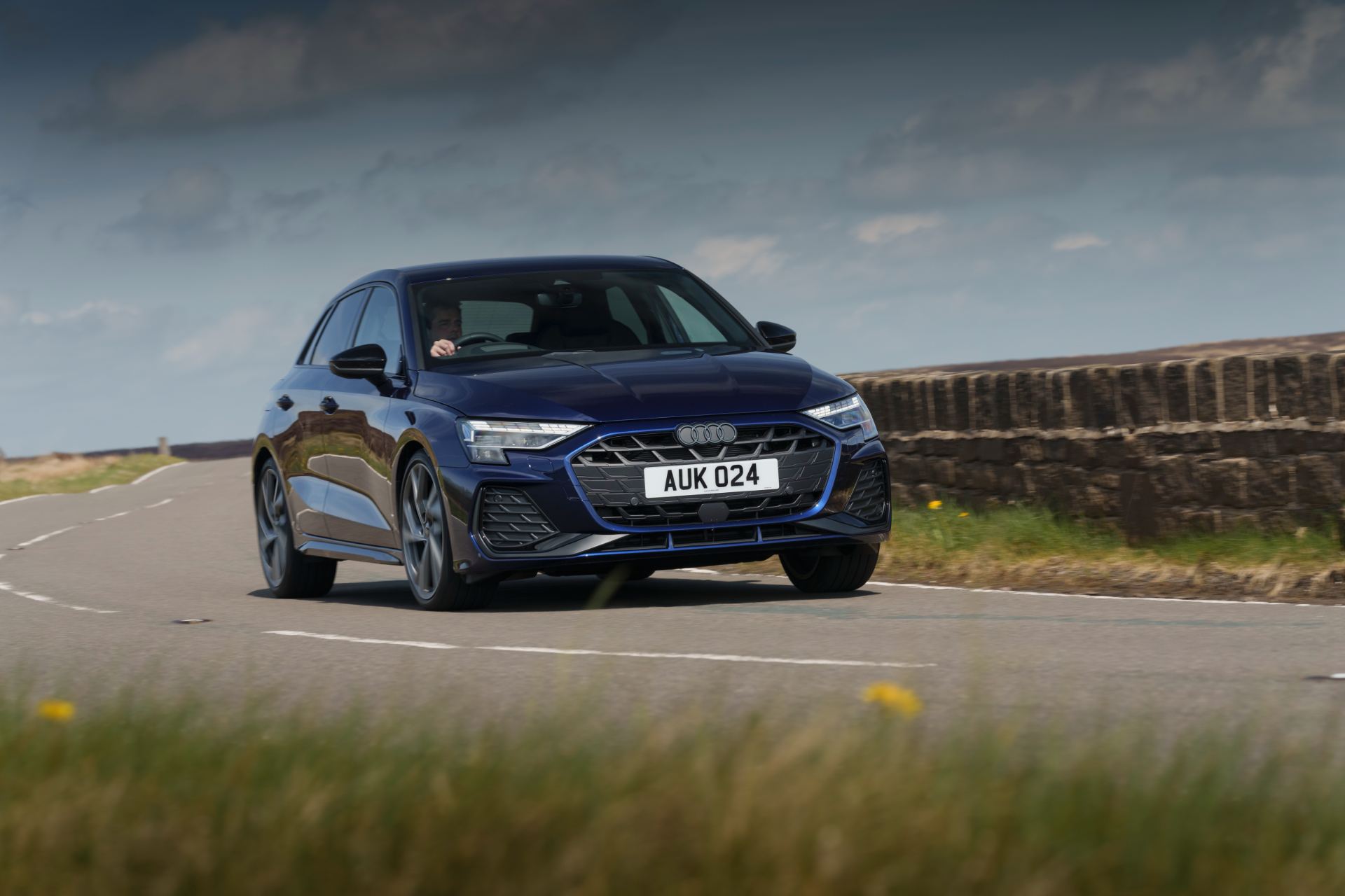 2025 audi a3 sportback driving front three quarter stone wall blue
