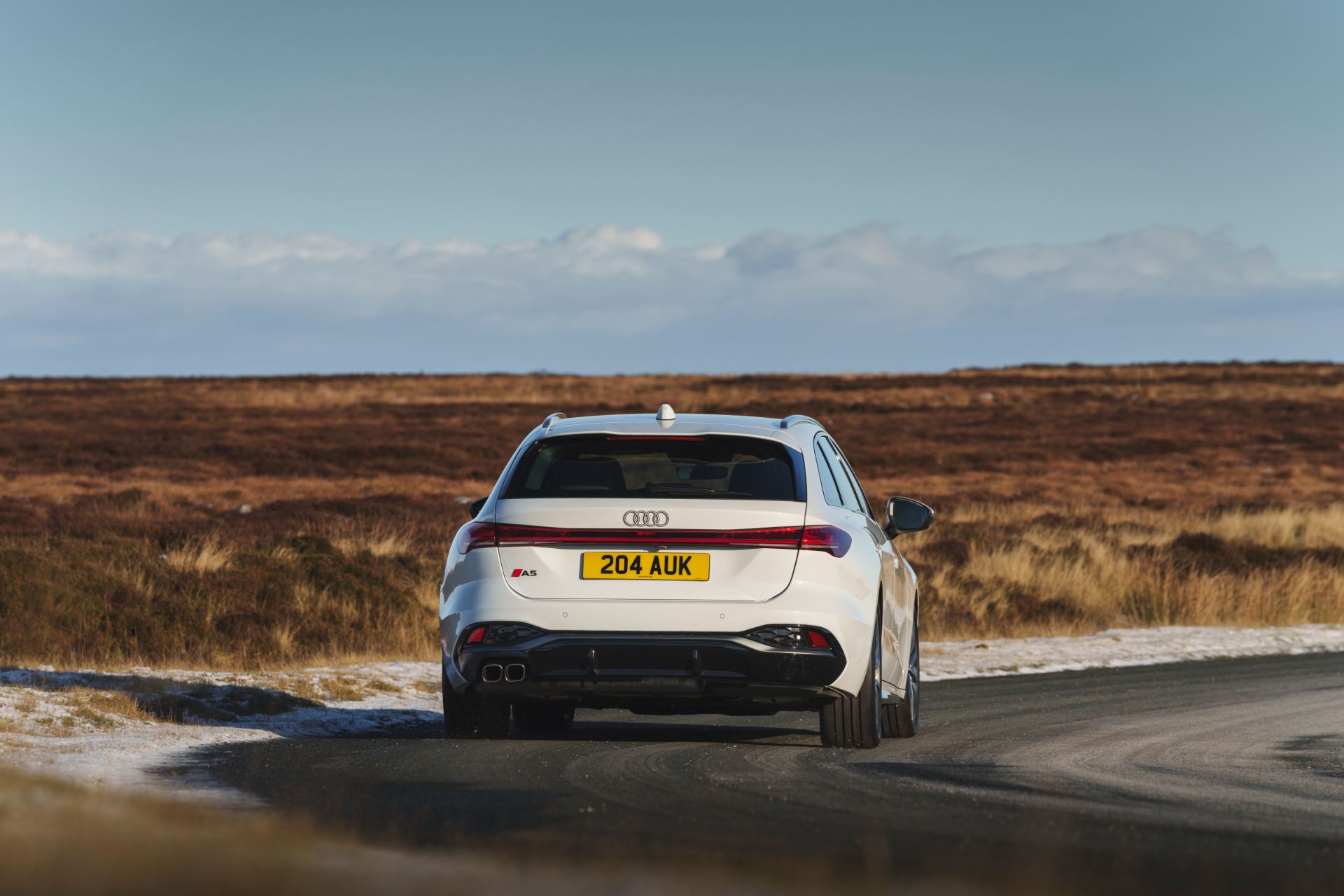 audi a5 avant driving rear moorland road white