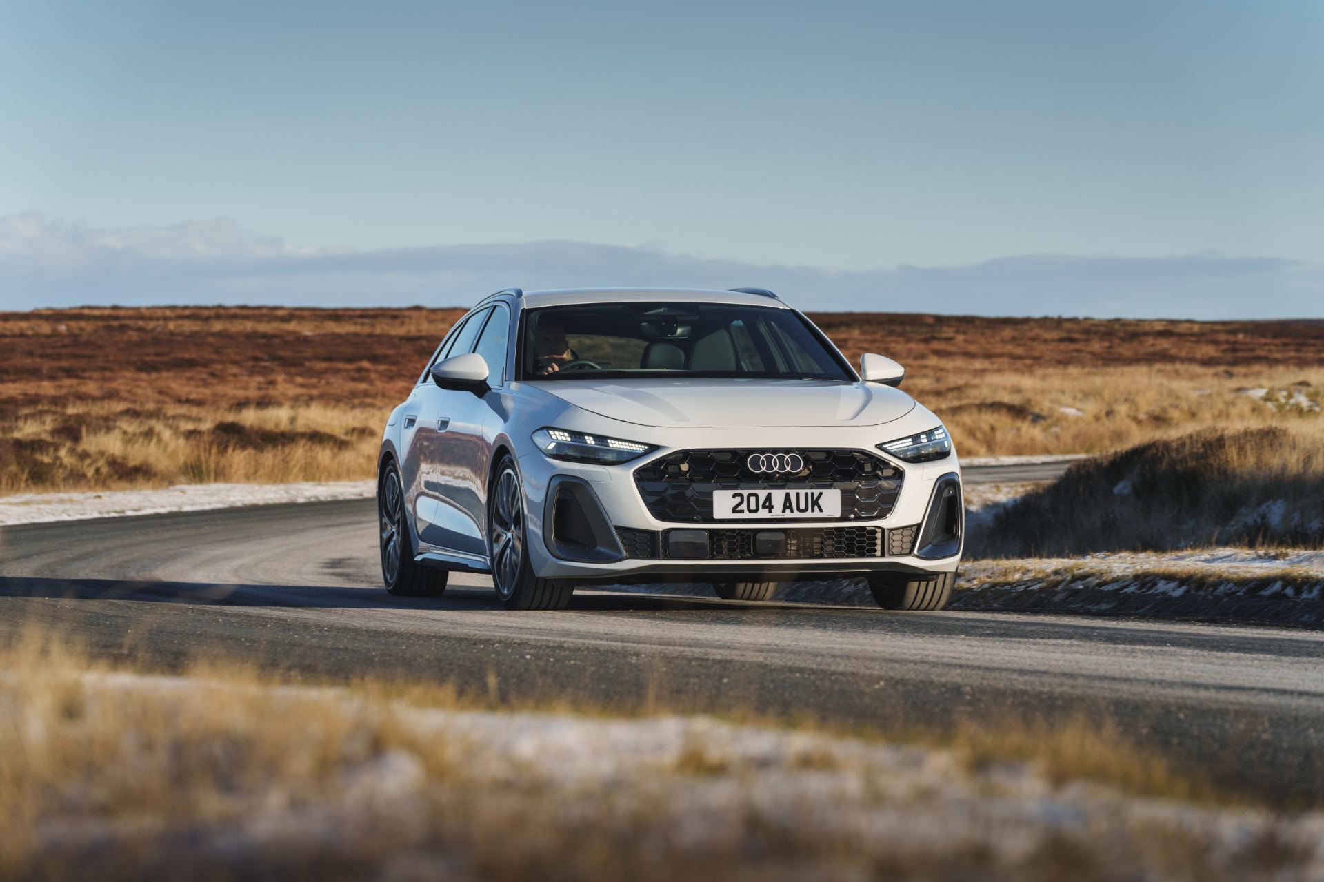 audi a5 avant driving front moorland road white
