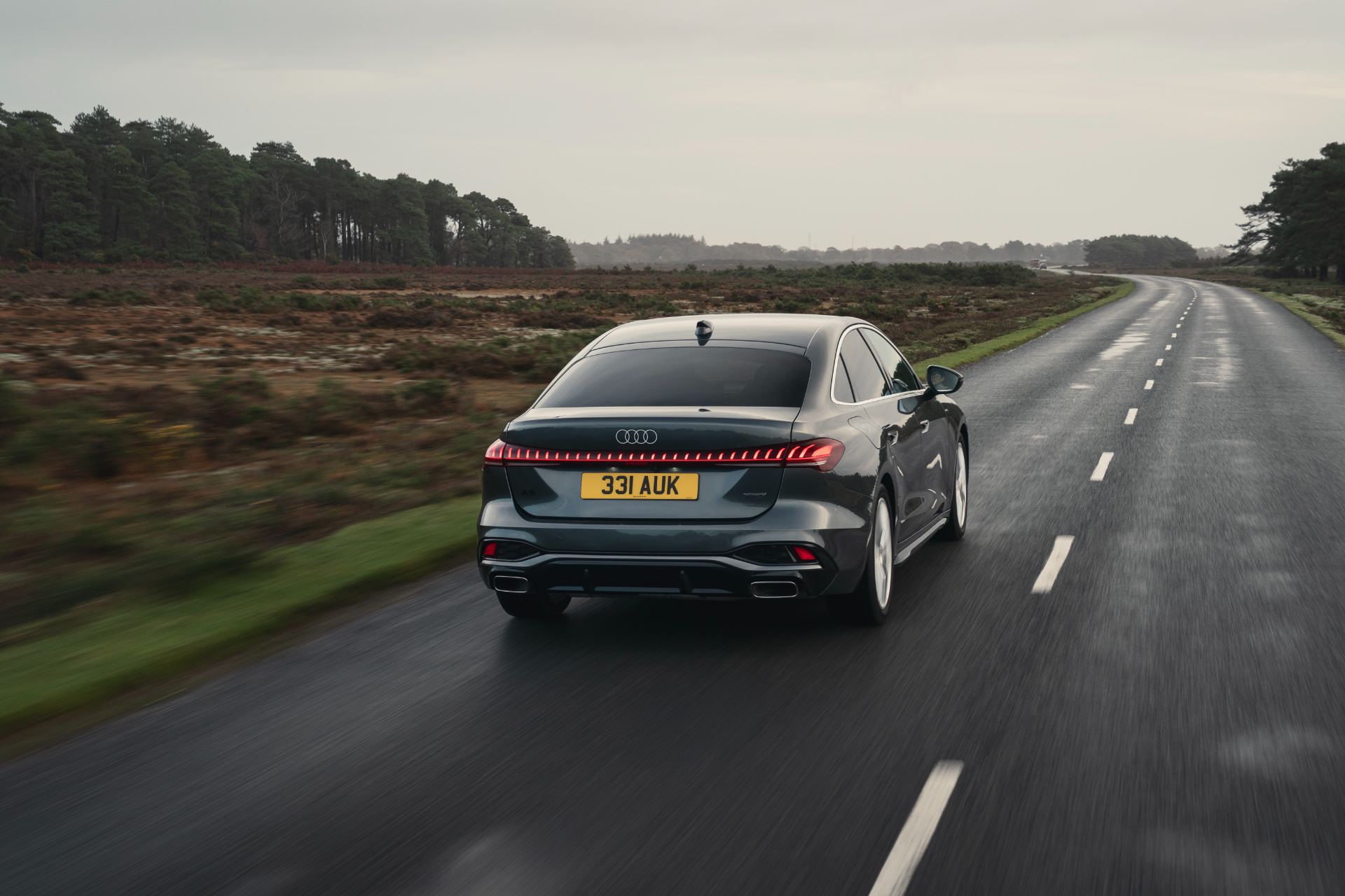 2026 audi a5 saloon e hybrid driving rear heath road grey