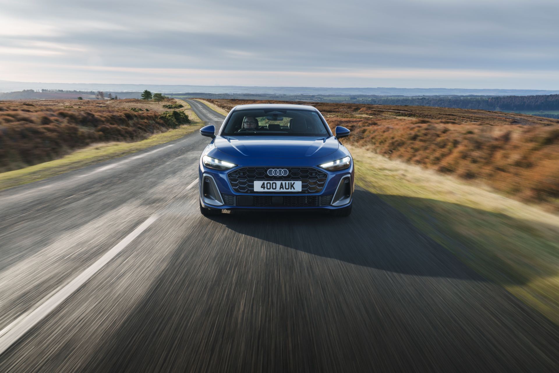 audi a5 saloon driving front moorland road blue