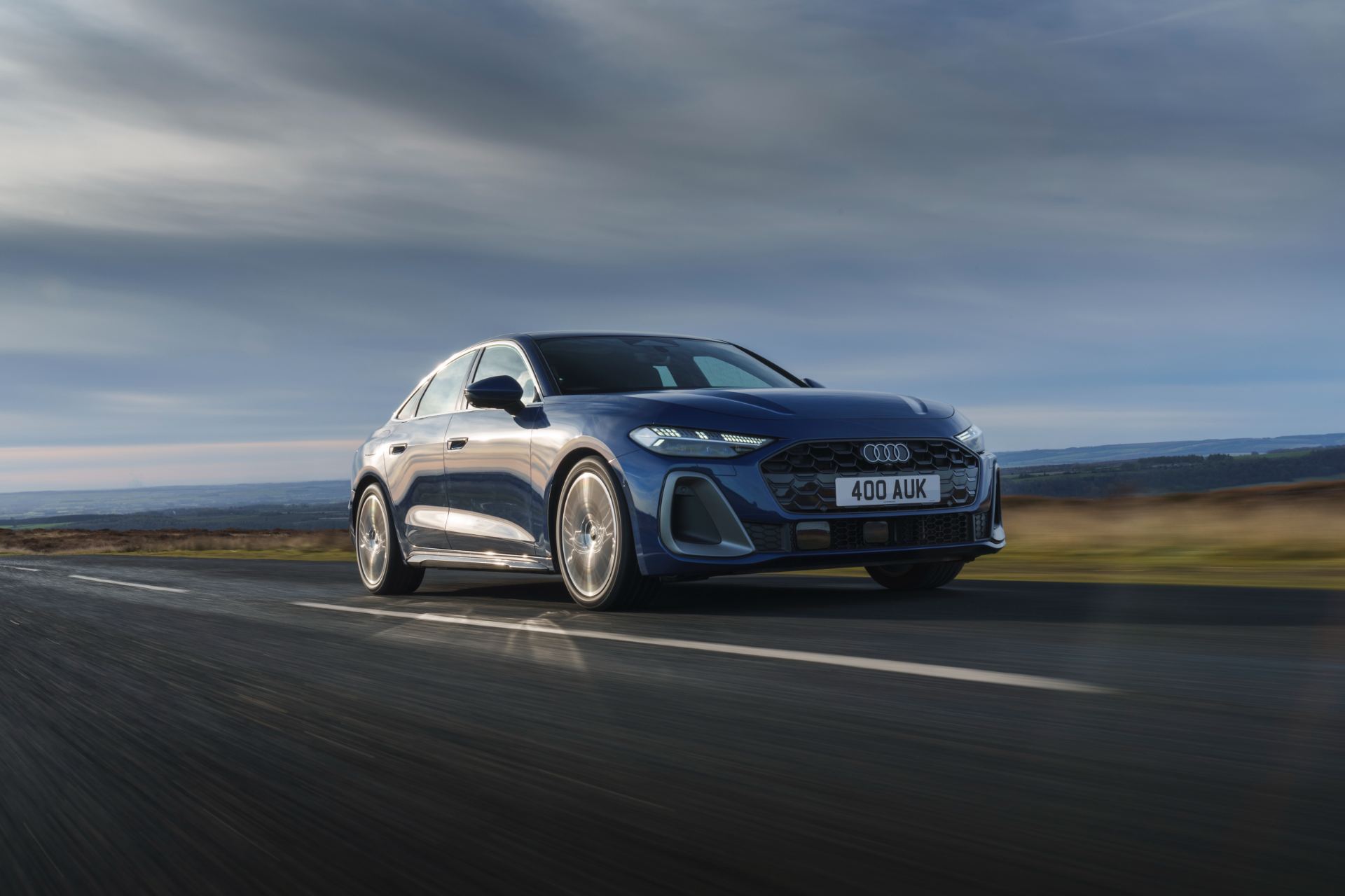 audi a5 saloon driving front three quarter moorland road blue