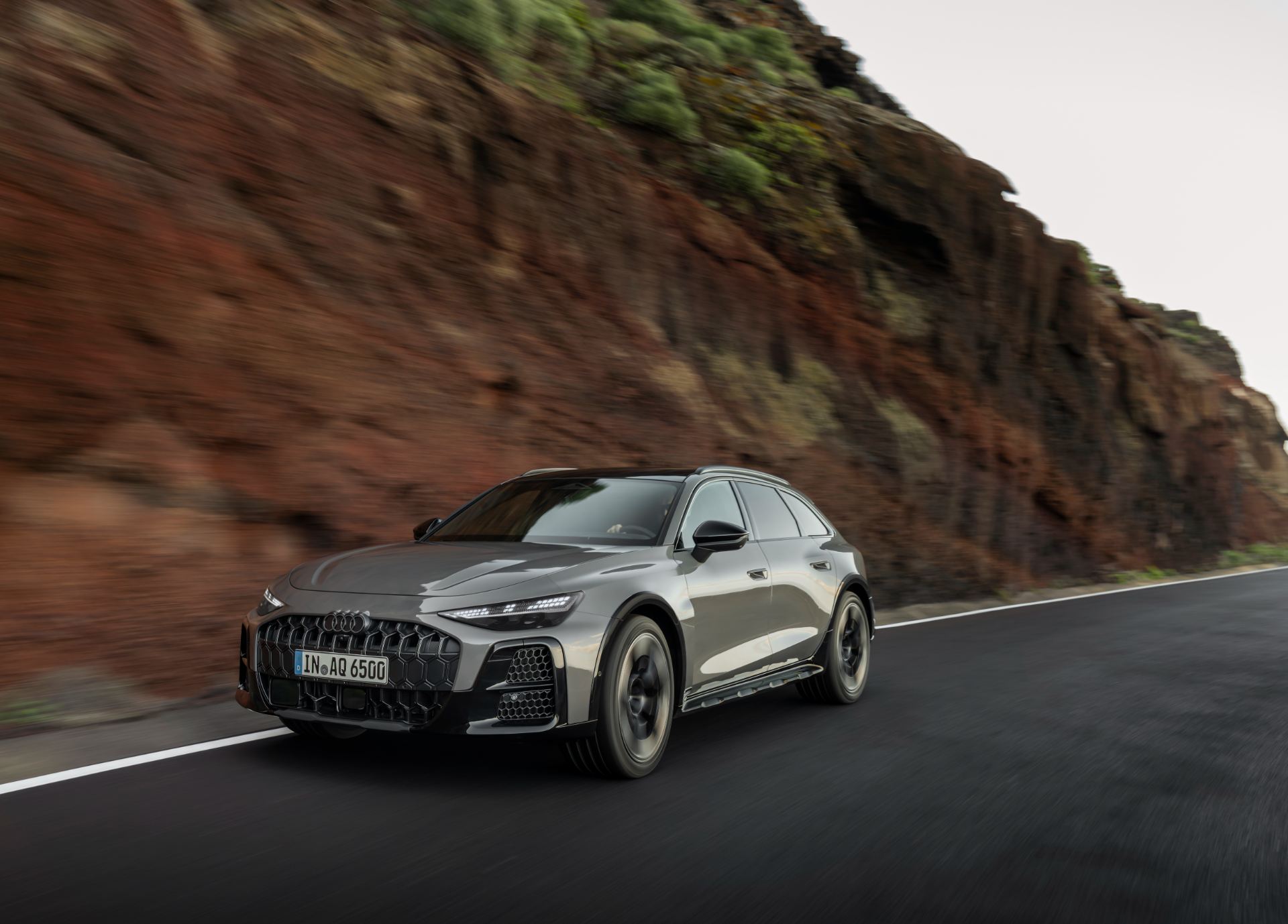 2026 audi a6 allroad driving front three quarter cliff road grey