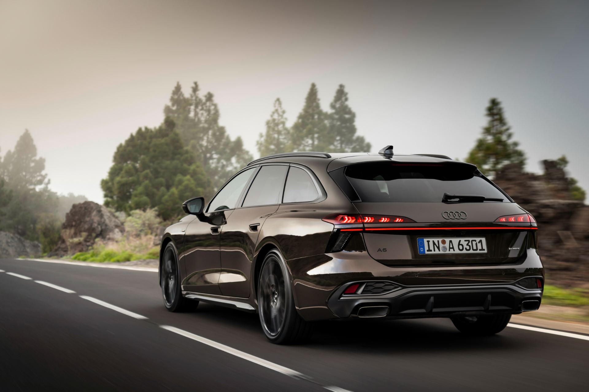 2026 audi a6 avant driving rear three quarter forest road brown