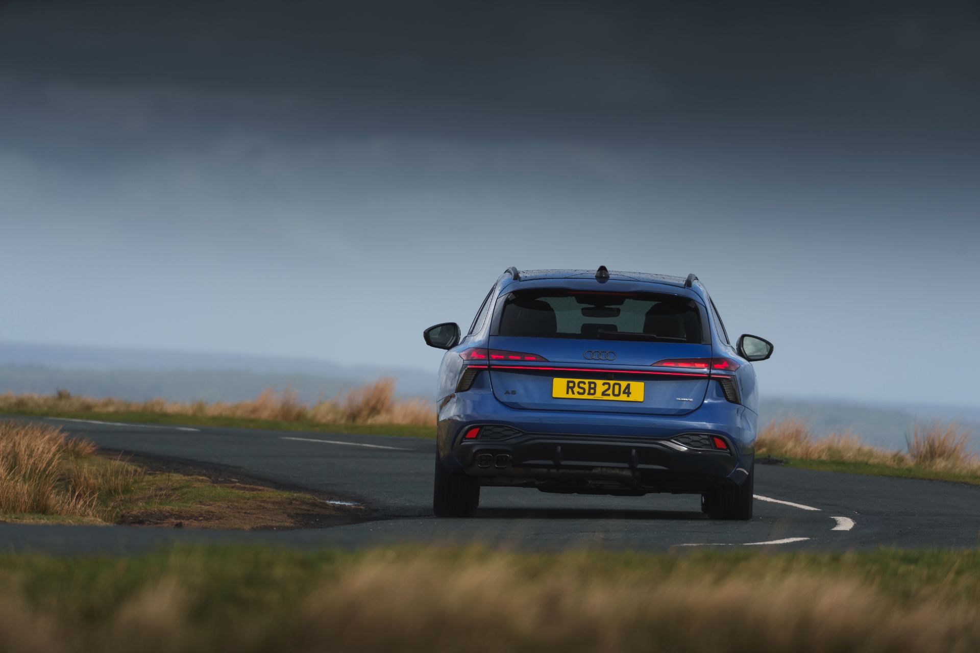 2026 audi a6 avant driving rear moorland bend blue