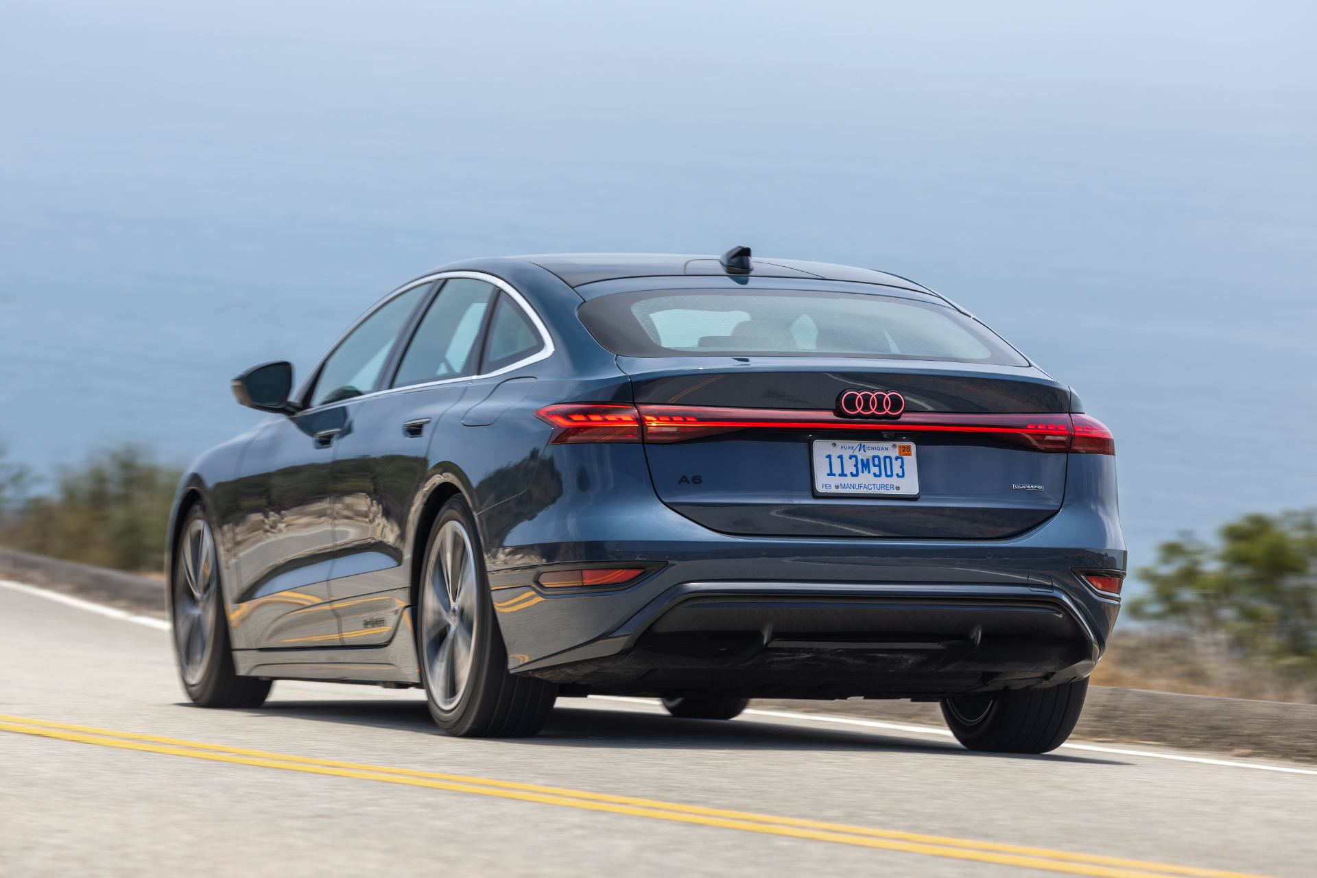 2027 audi a6 sportback e tron driving rear coastal road grey