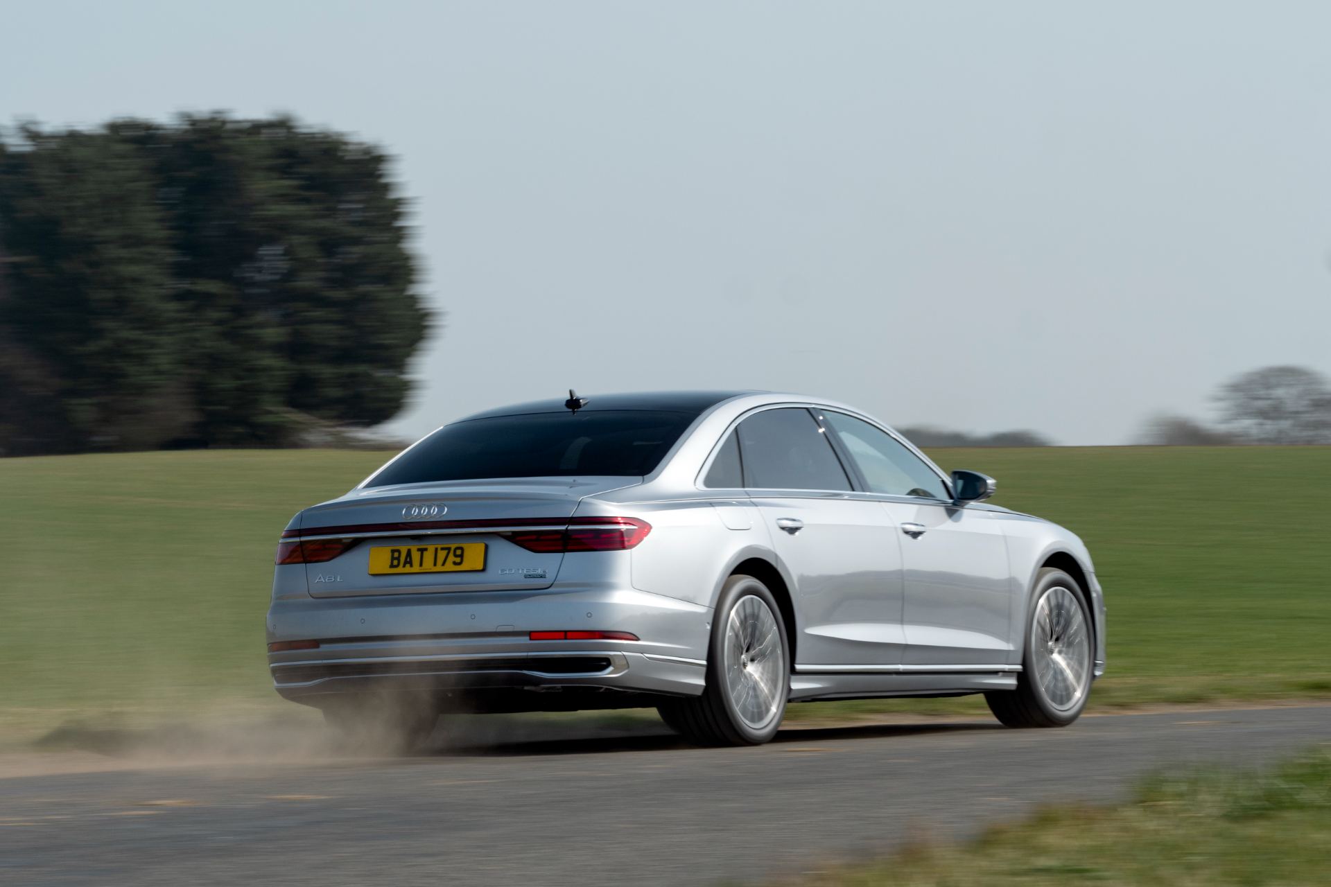 2025 audi a8 60 tfsi e driving rear three quarter silver