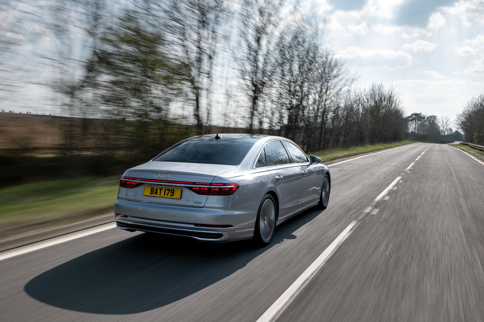 2025 audi a8 60 tfsi e driving rear road silver