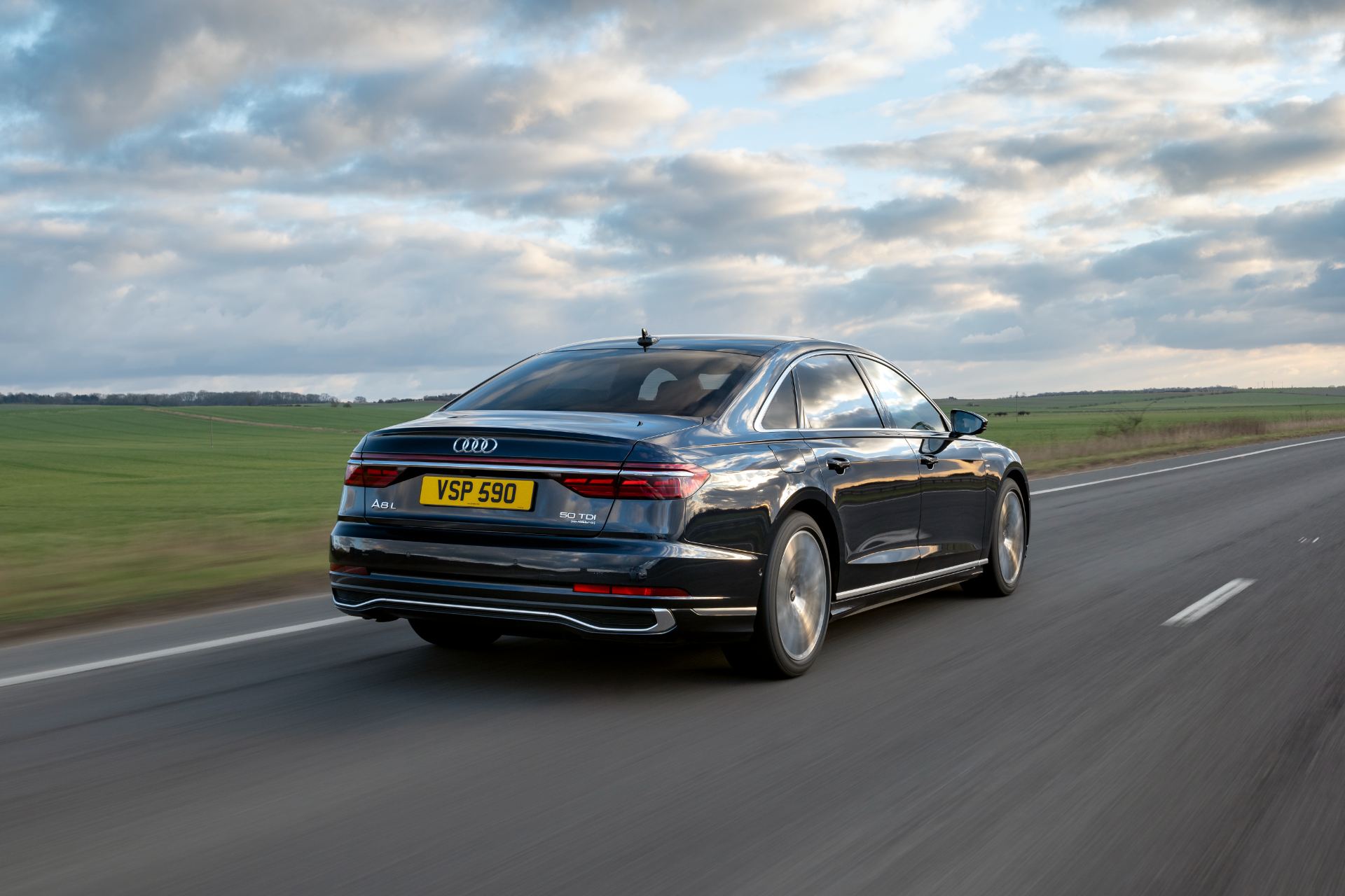 2025 audi a8 l driving rear three quarter clouds black