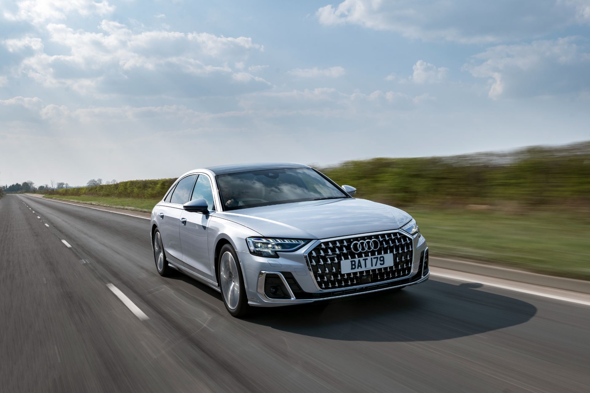 2025 audi a8 60 tfsi e driving front three quarter road silver