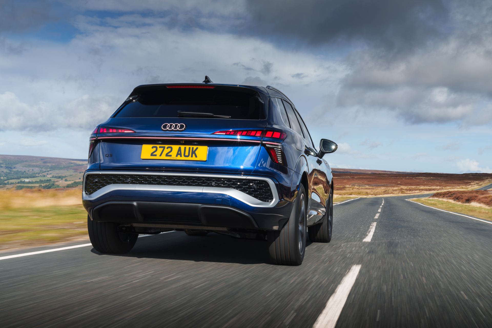 2026 audi q3 e hybrid driving rear moorland road blue