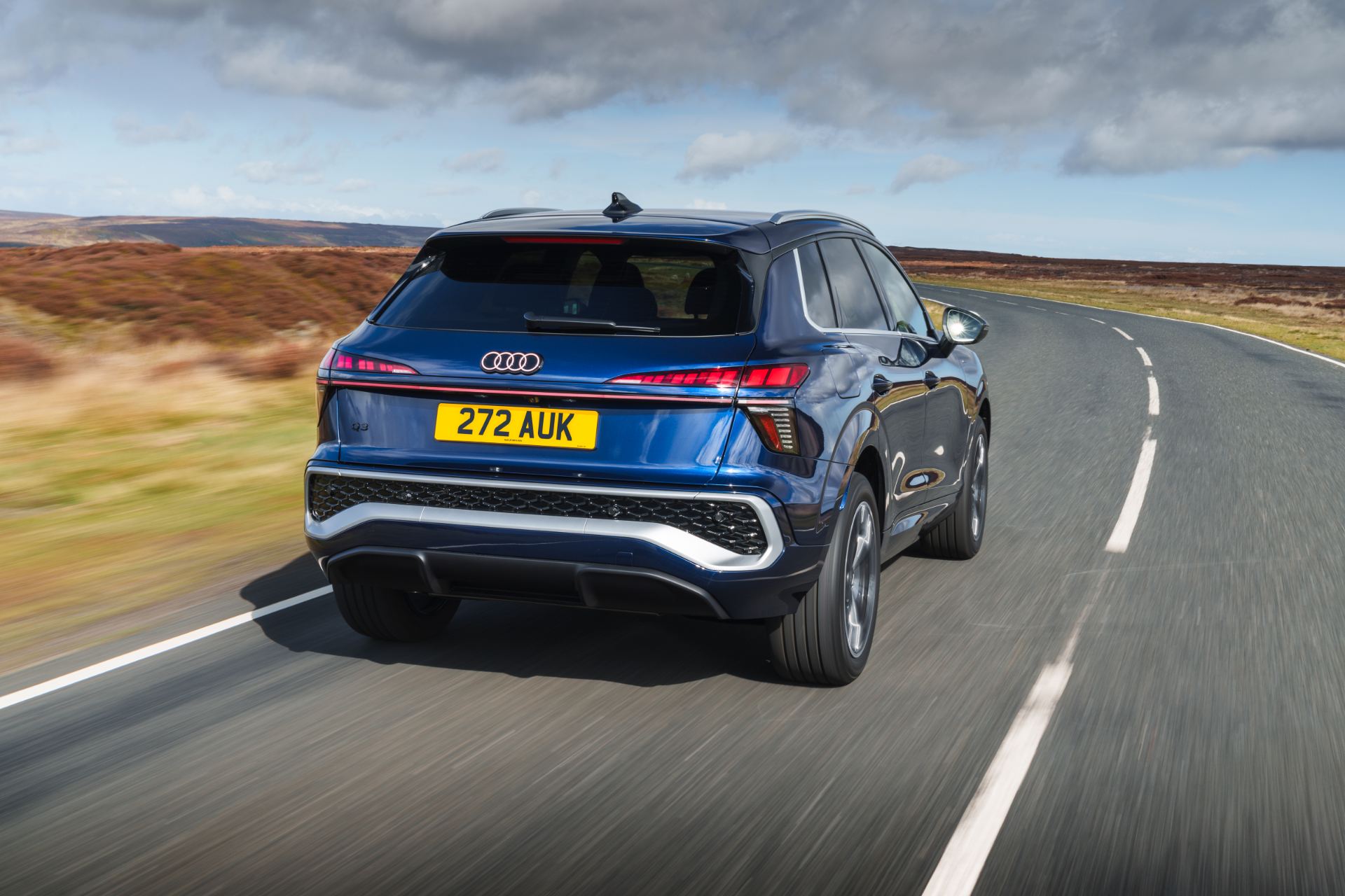 2026 audi q3 e hybrid driving rear three quarter moorland road blue