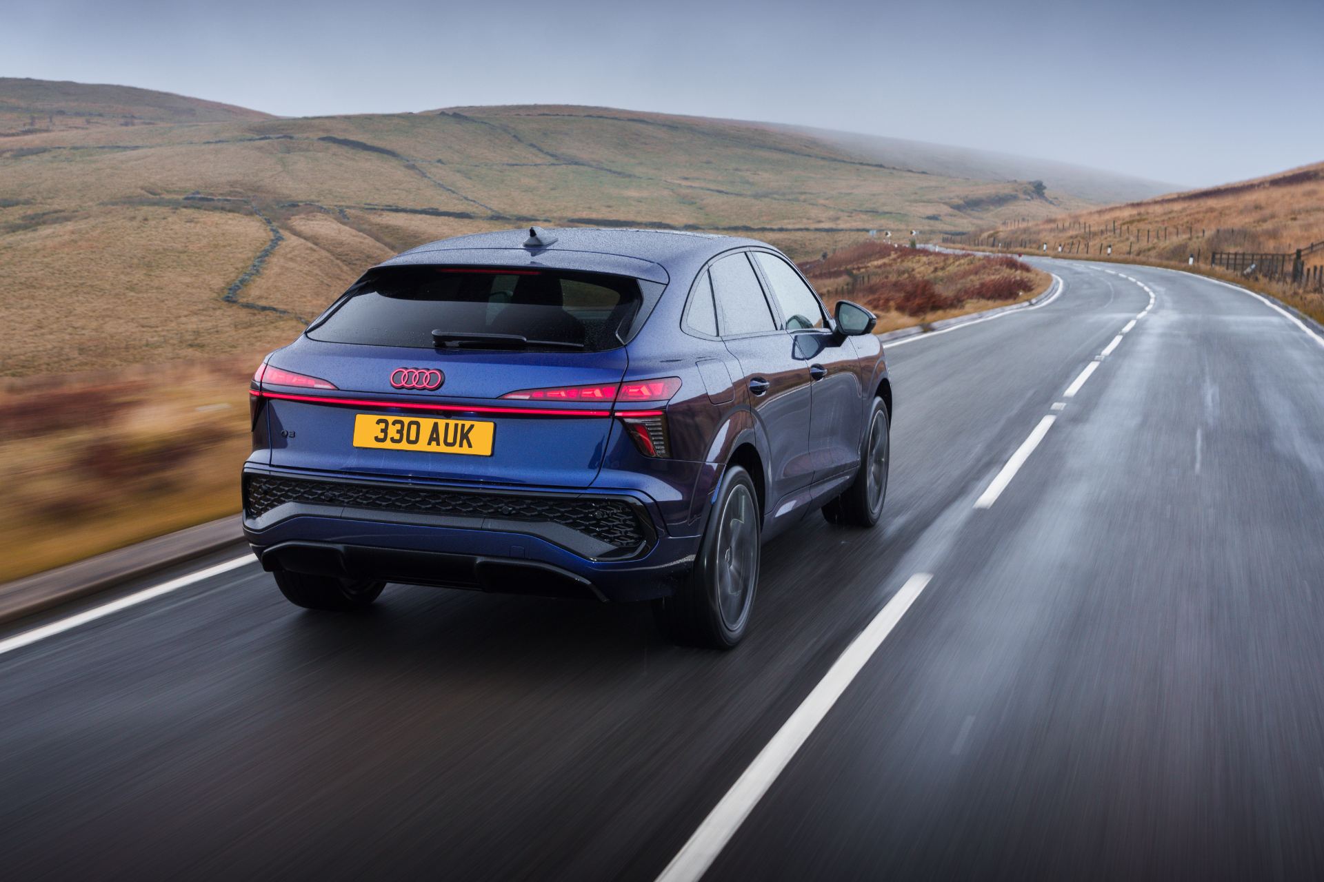 2026 audi q3 sportback e hybrid driving rear three quarter wet road blue