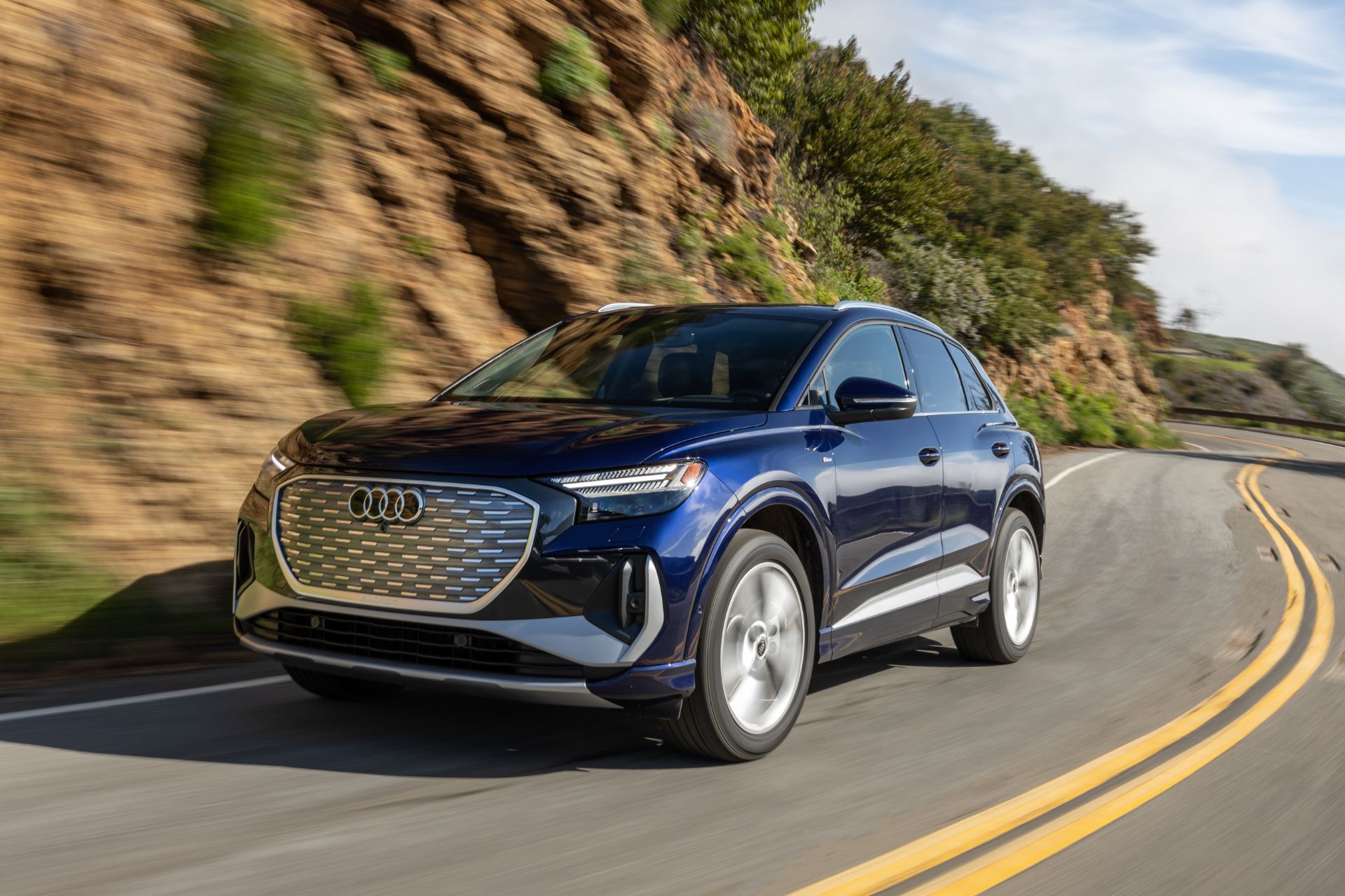 2026 audi q4 e tron driving front three quarter canyon road blue