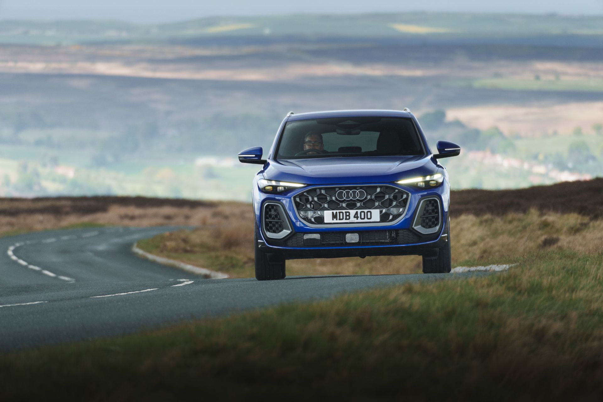 2026 audi q5 sportback e hybrid driving front countryside blue
