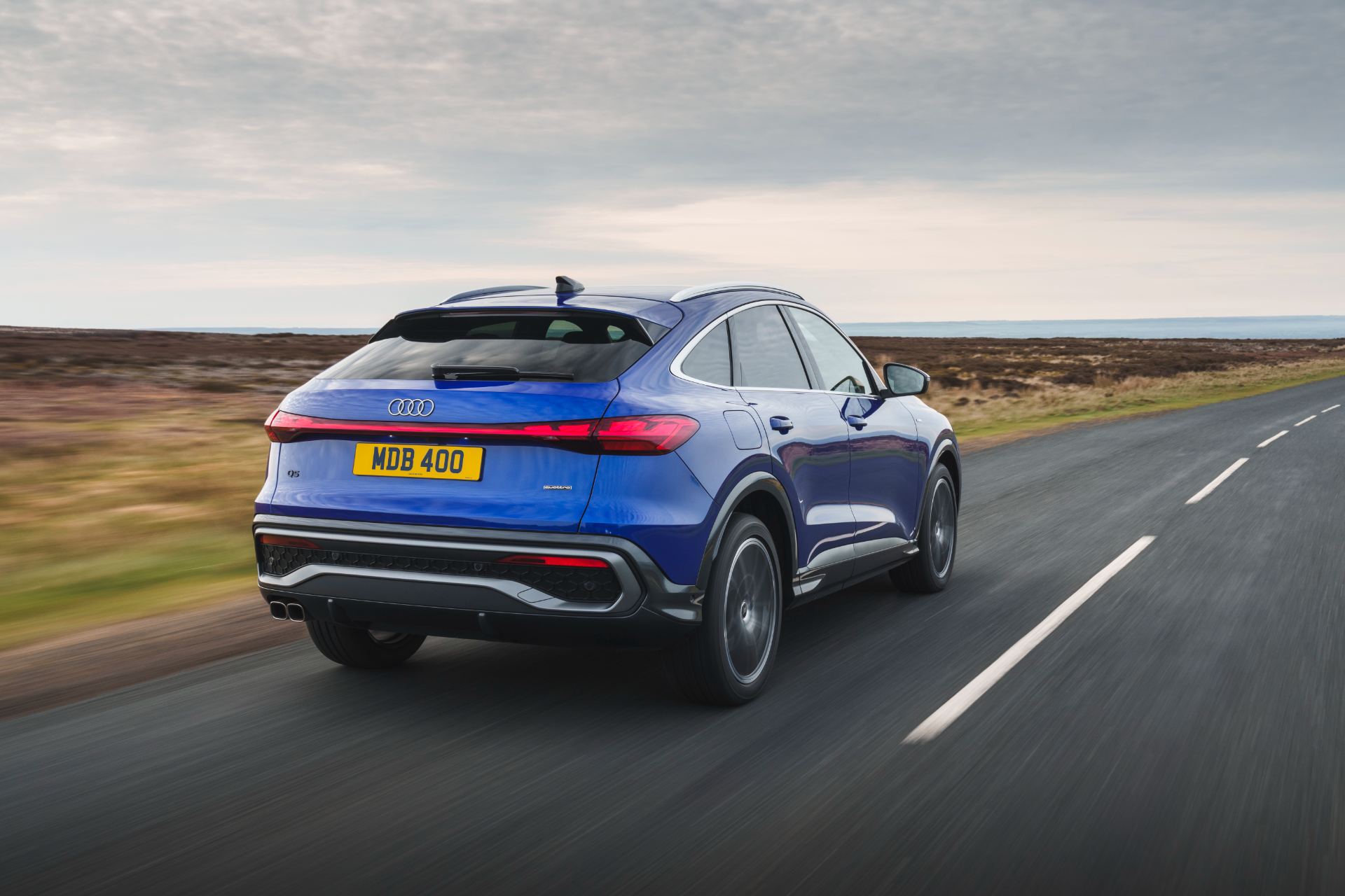 2026 audi q5 sportback e hybrid driving rear three quarter blue