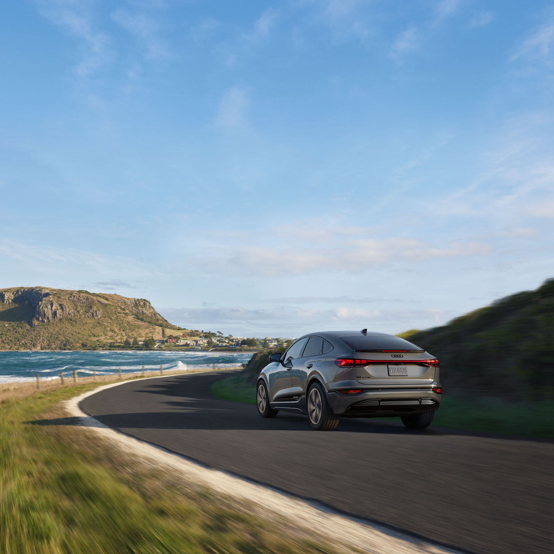 2027 audi q6 sportback e tron driving rear three quarter coastal road grey