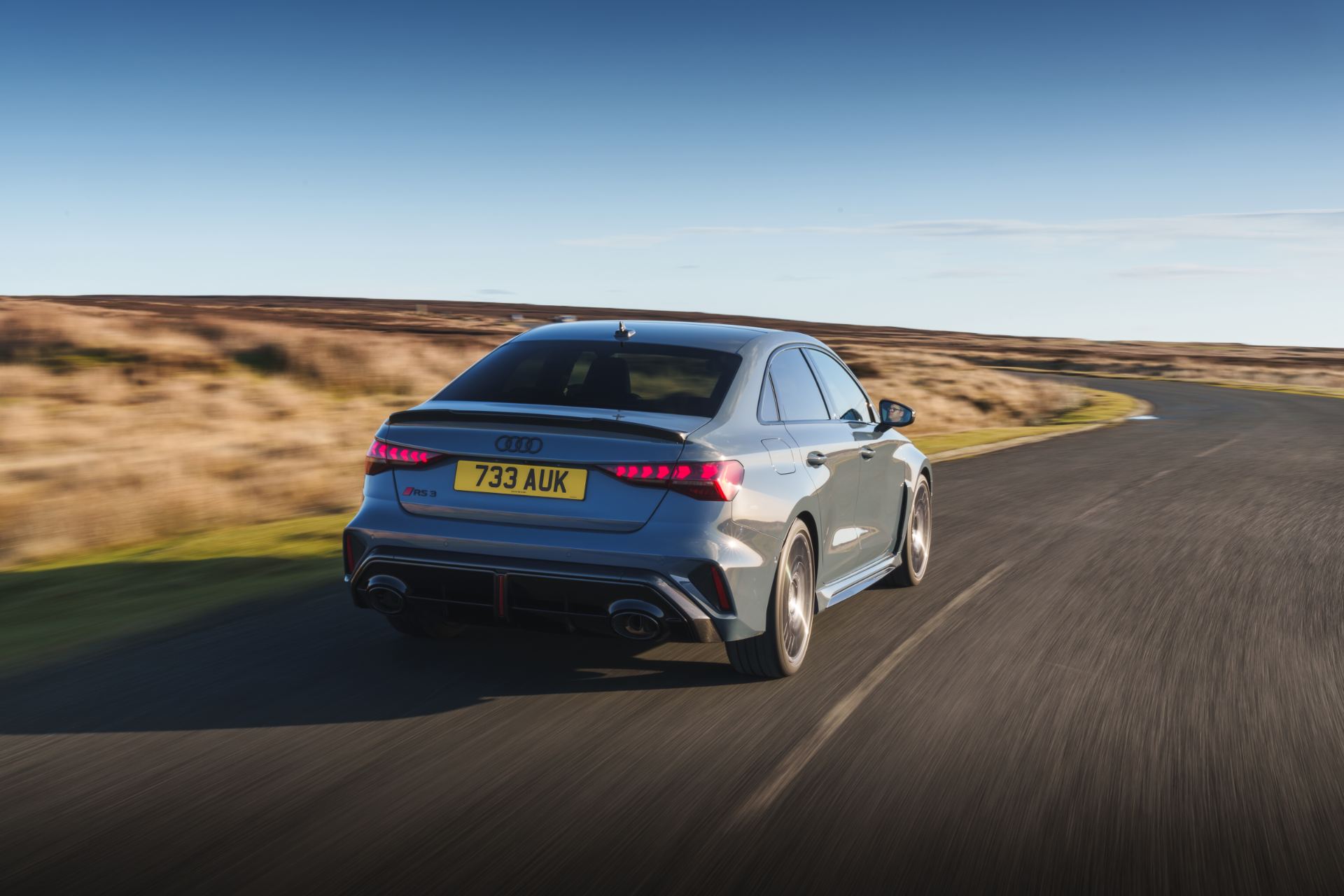 2025 audi rs 3 saloon driving rear three quarter moorland road grey