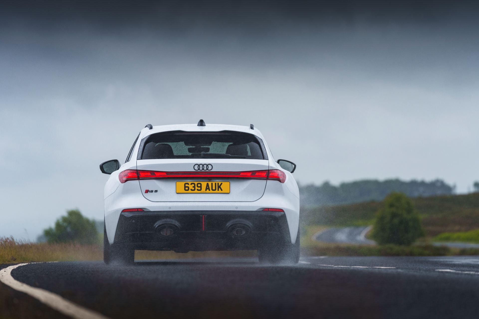 2026 audi rs 5 avant driving rear wet road white