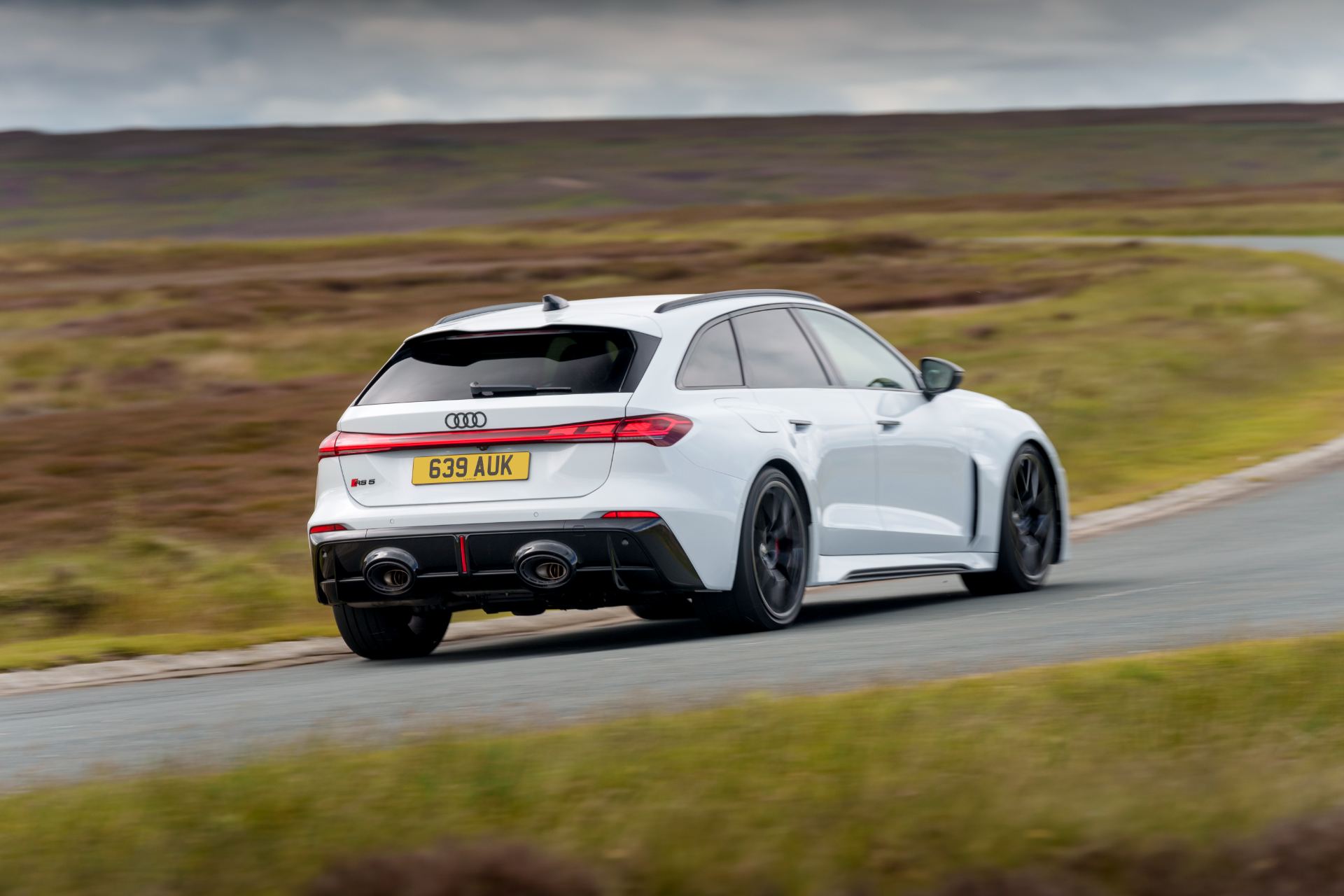 2026 audi rs 5 avant driving rear three quarter moorland road white