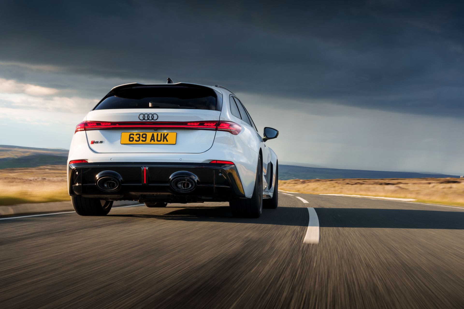 2026 audi rs 5 avant driving rear moorland road white
