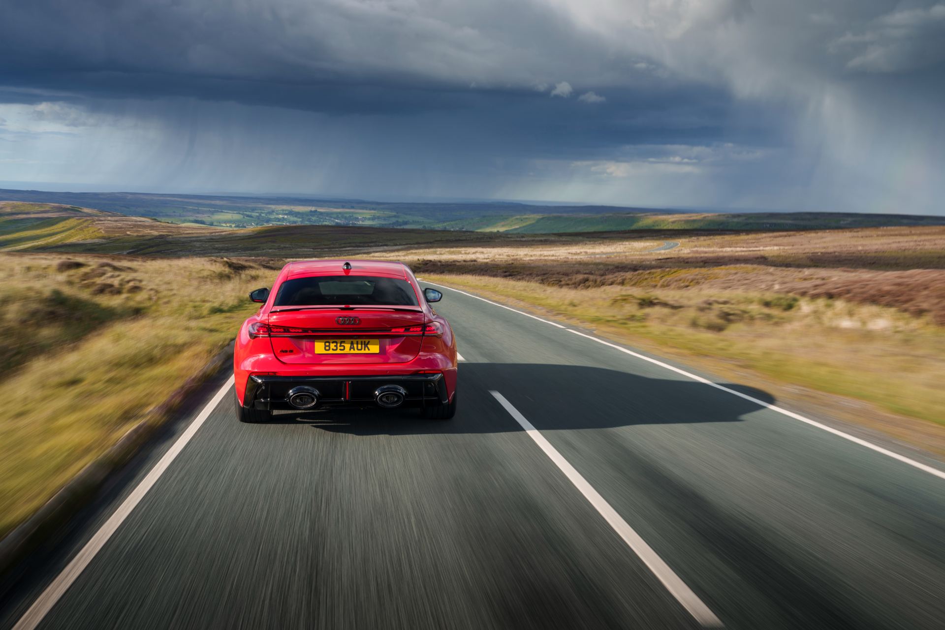 2026 audi rs 5 saloon driving rear moorland road red