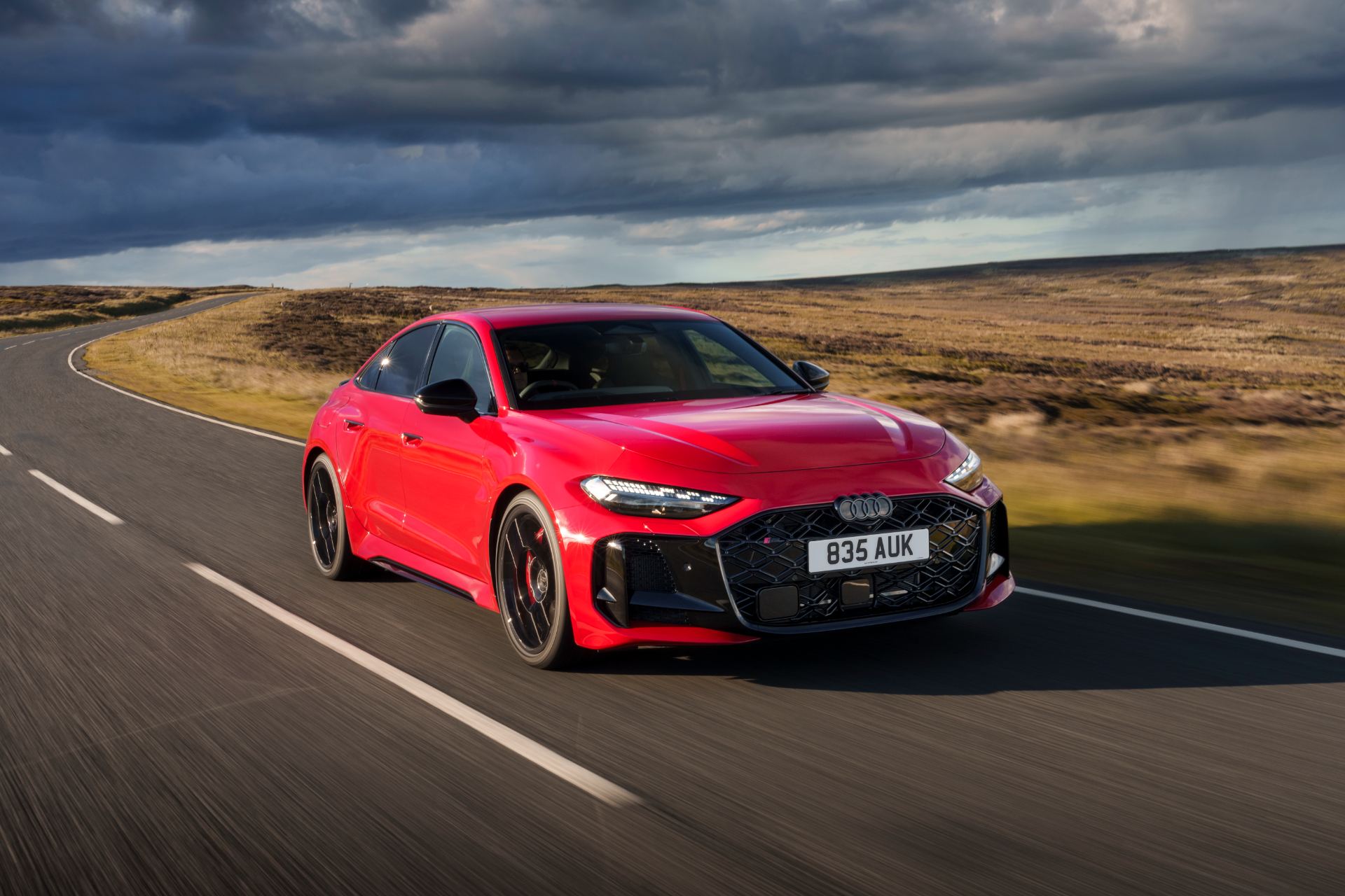 2026 audi rs 5 saloon driving front three quarter moorland road red