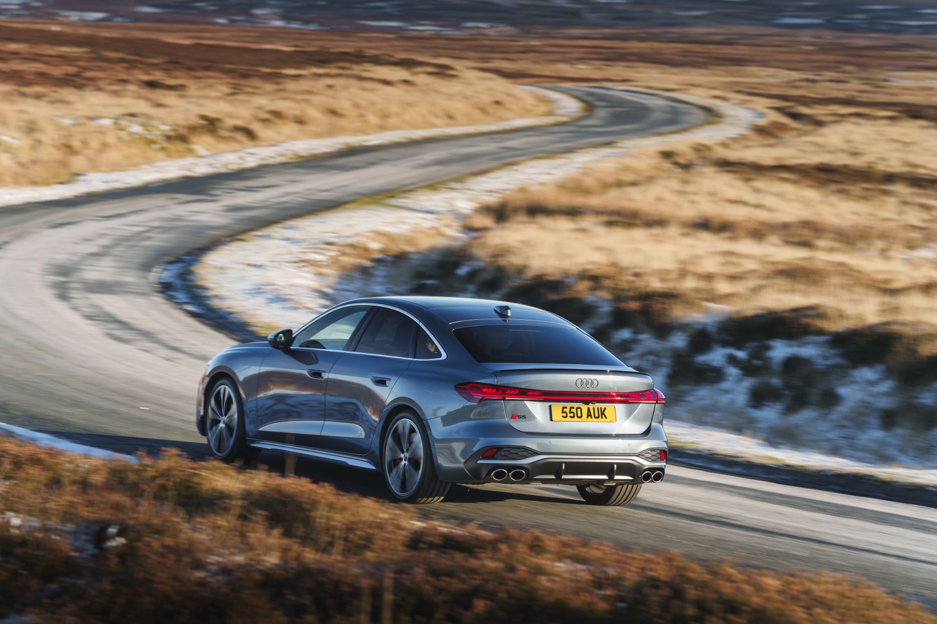 2026 audi s5 saloon driving rear three quarter winding road grey