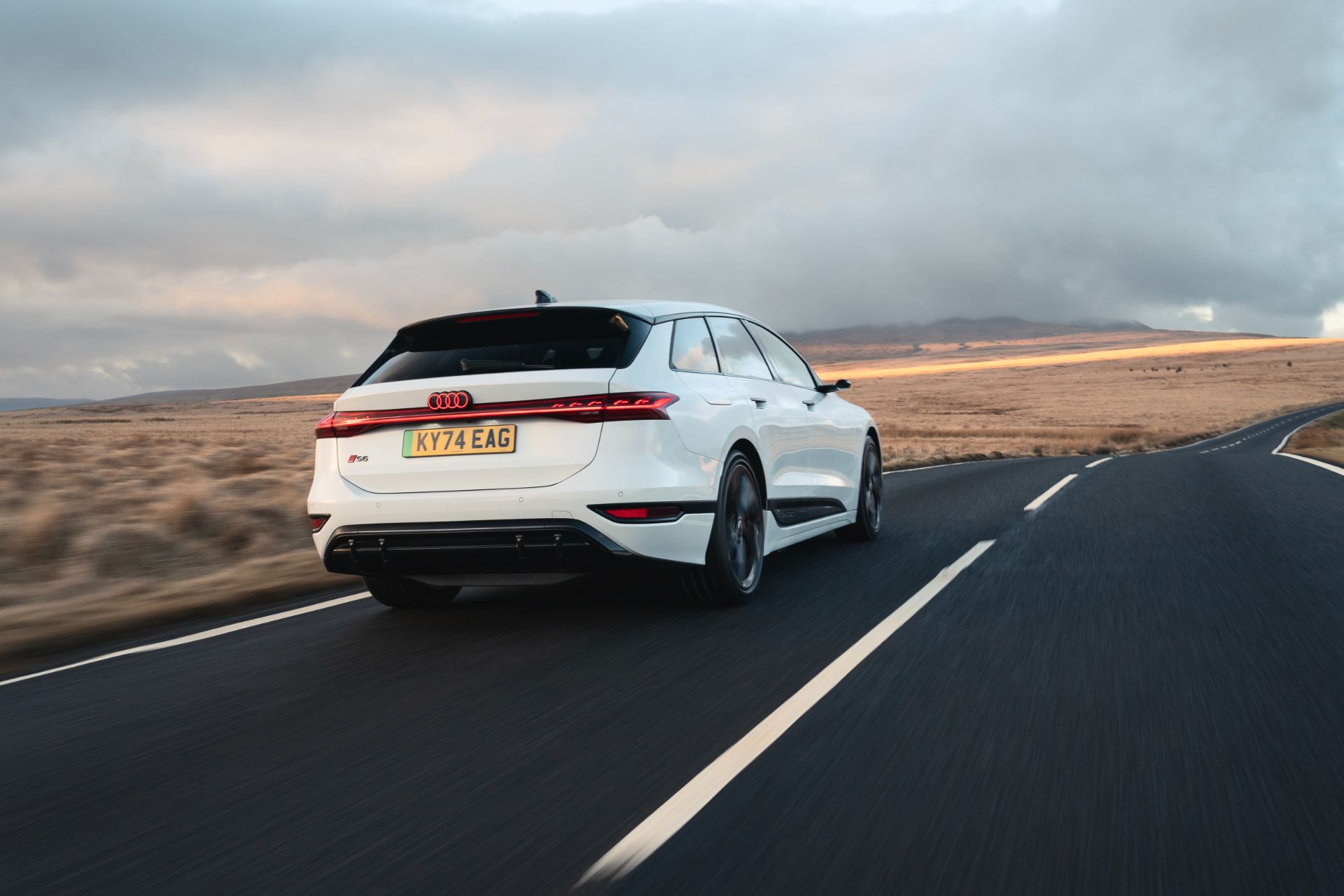 2026 audi s6 avant e tron driving rear three quarter moorland road white
