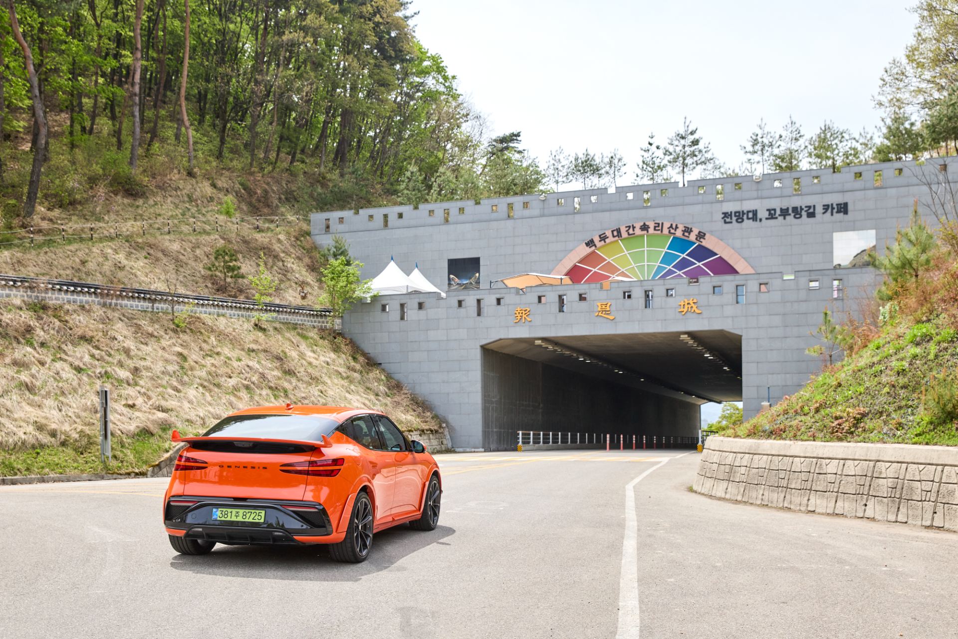 Rear three-quarter view showing the winglet-style rear spoiler and Magma-specific aero, in Magma Orange