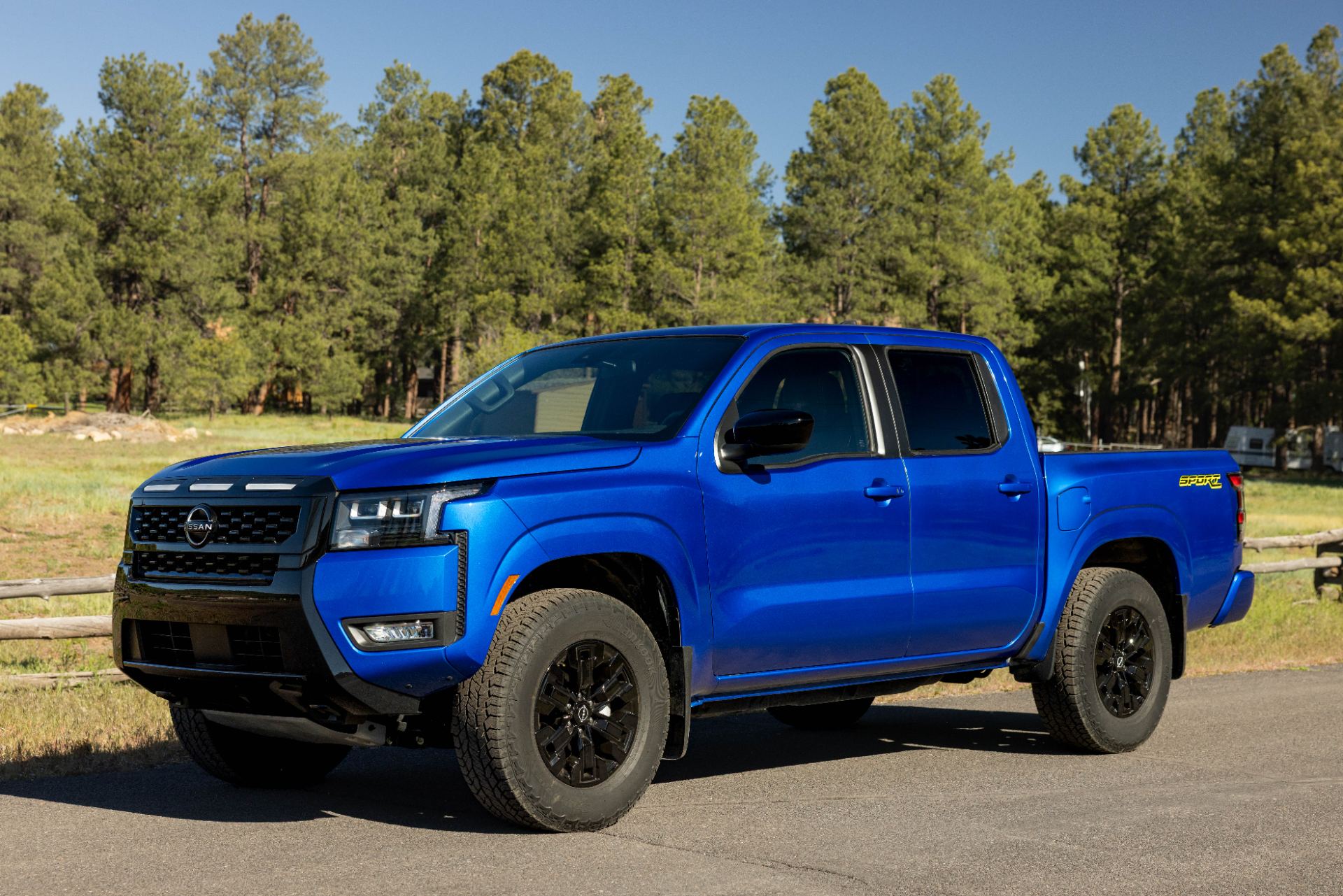 2027 Nissan Frontier PRO-4X with tailgate down at a game-day tailgate scene, official press photo